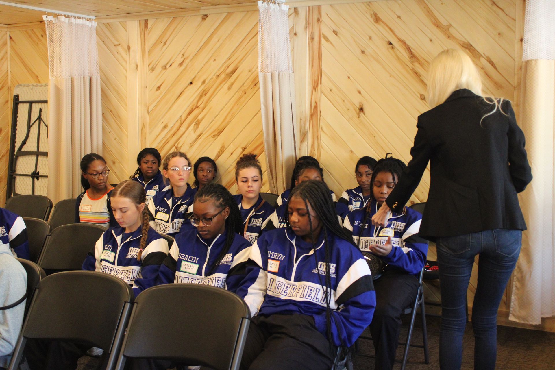A woman is standing in front of a group of people sitting in chairs.