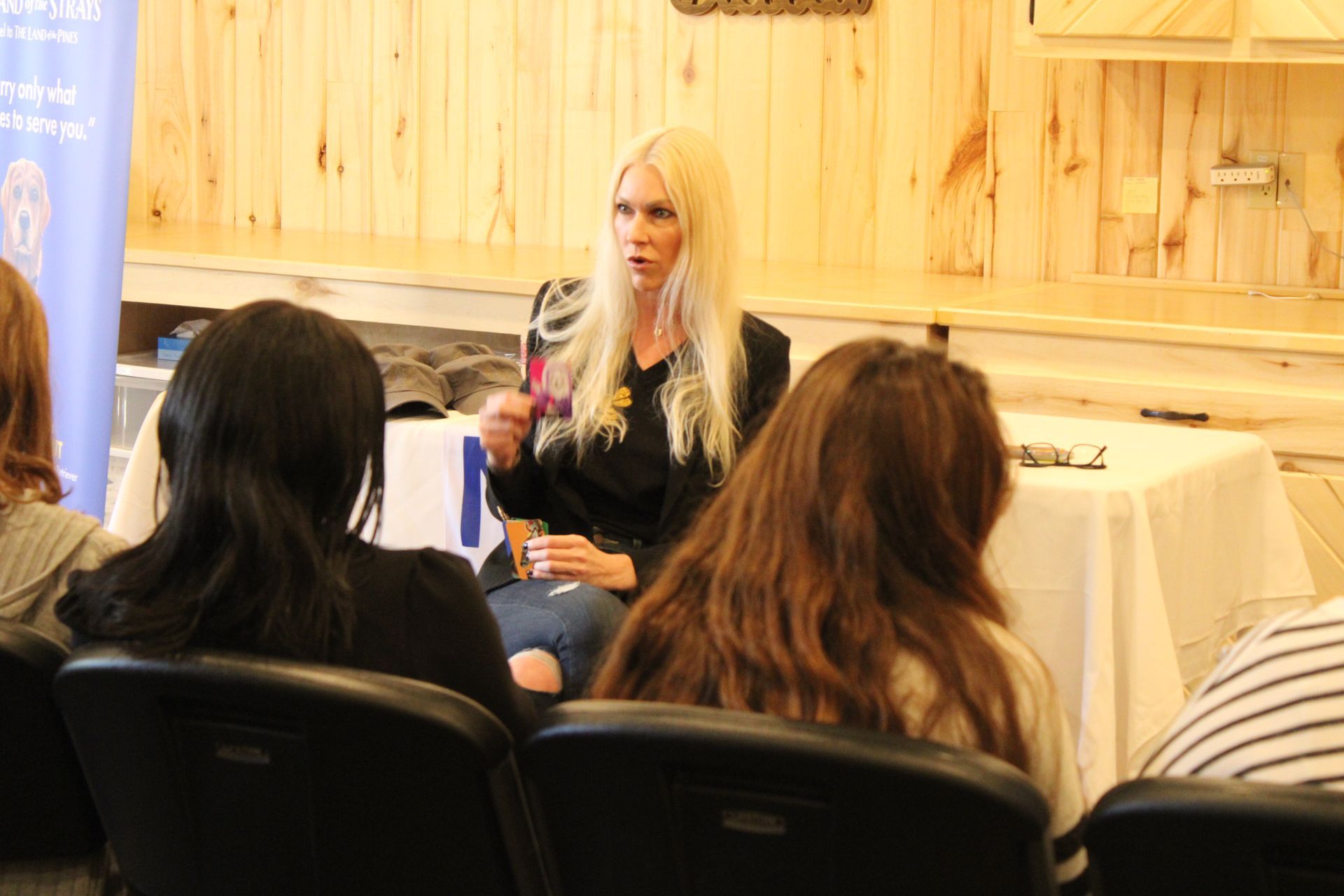 A woman is sitting at a table talking to a group of people.