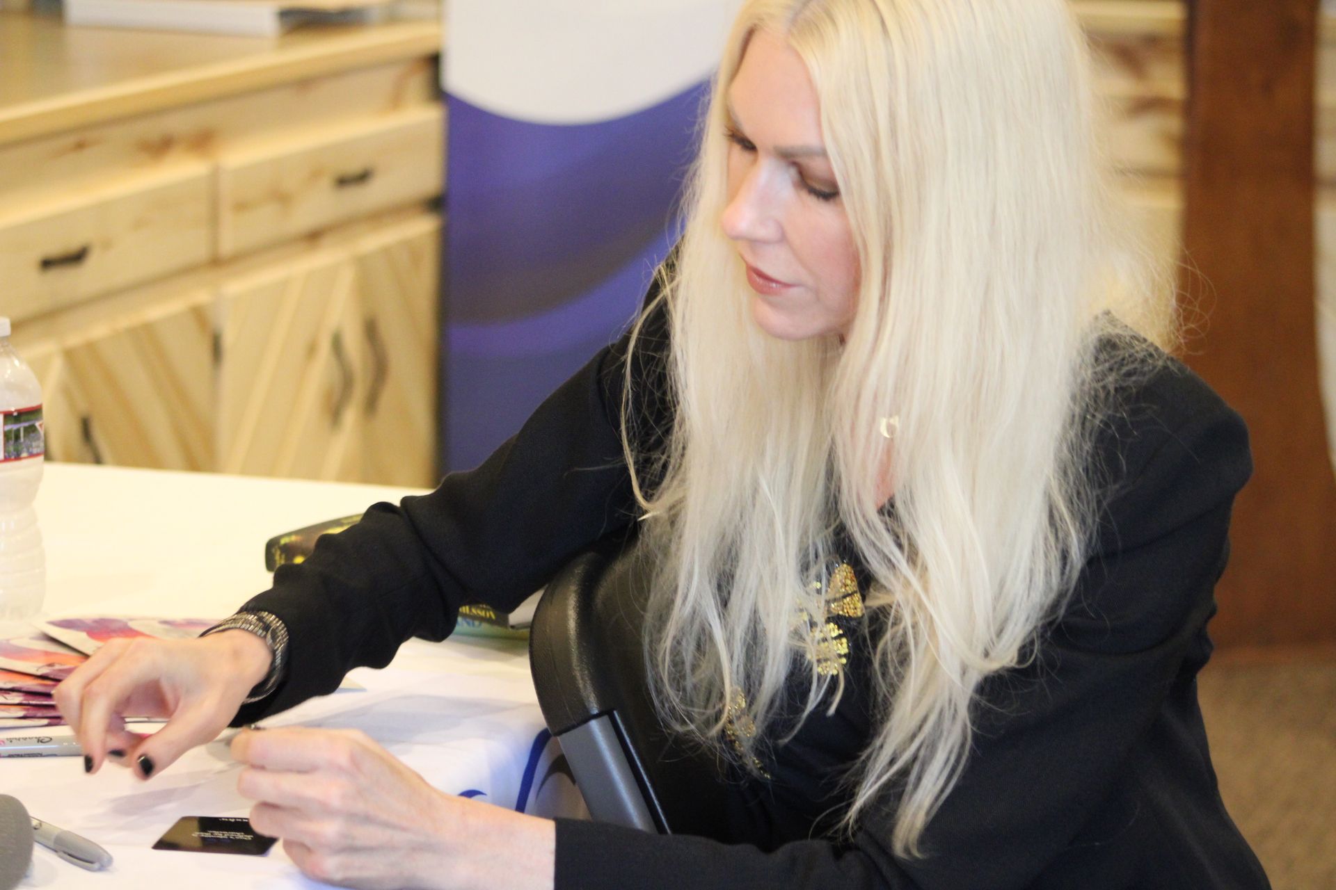 A woman with blonde hair is sitting at a table