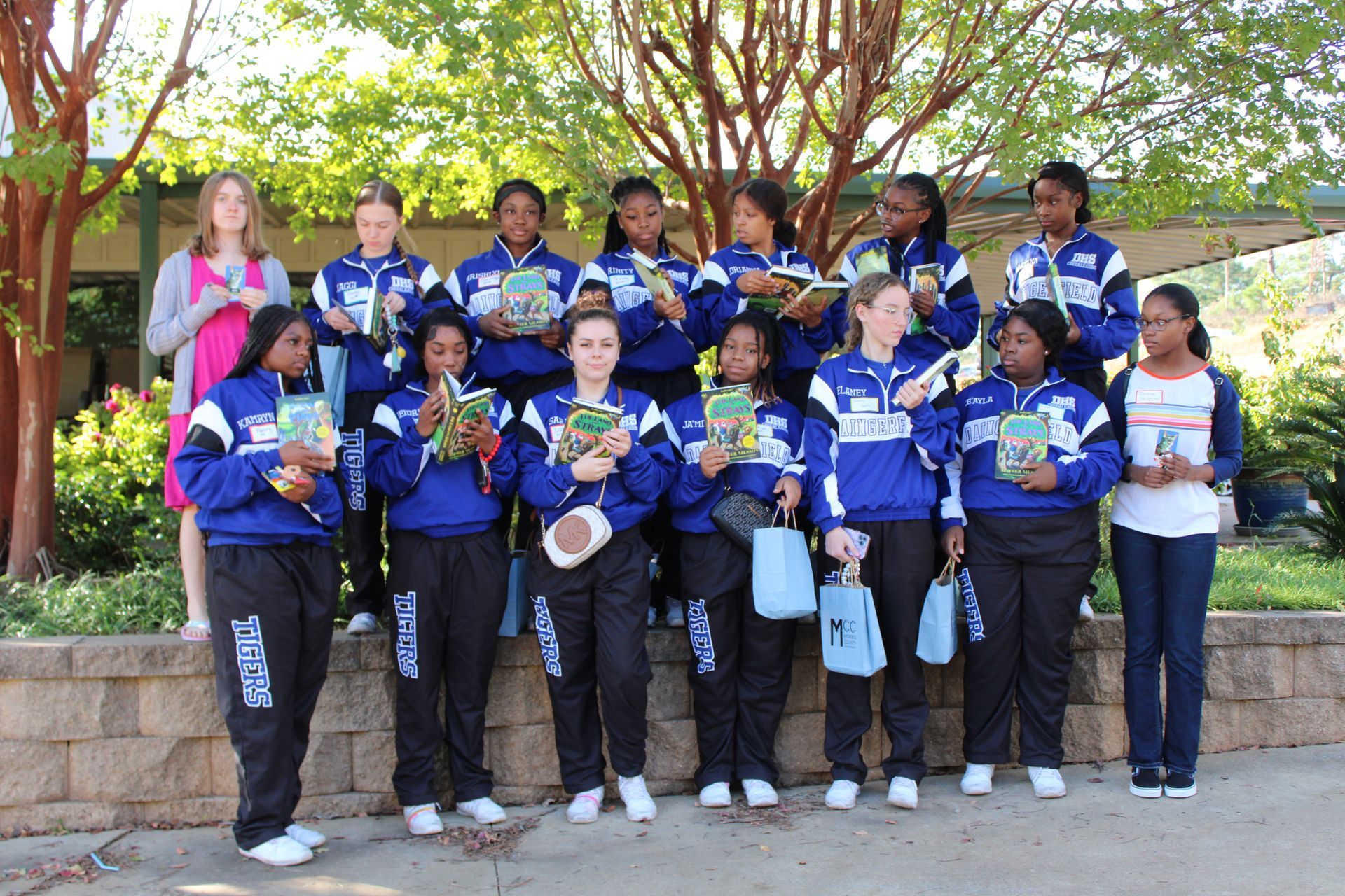 A group of girls standing next to each other holding books
