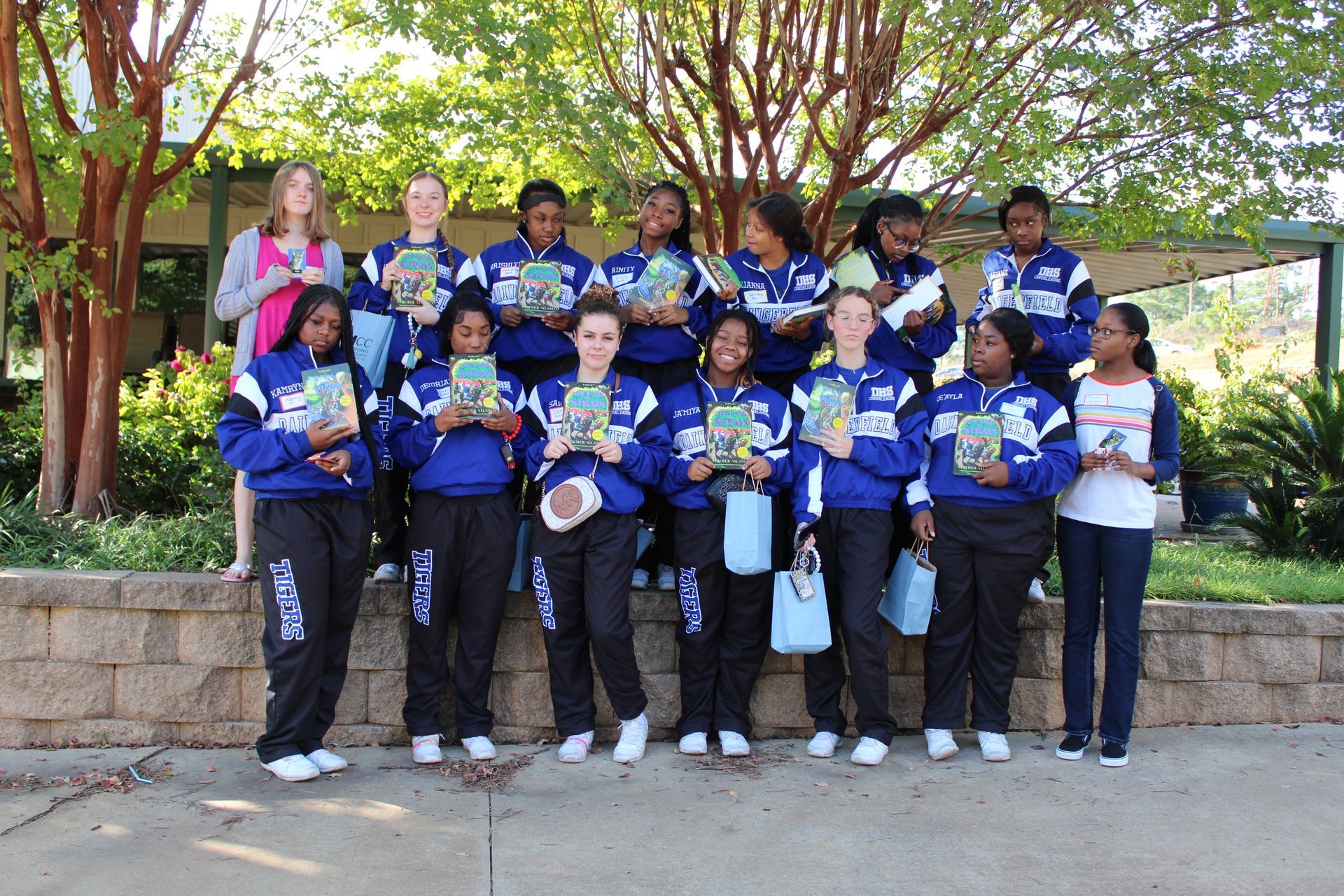 A group of girls are holding books and posing for a picture