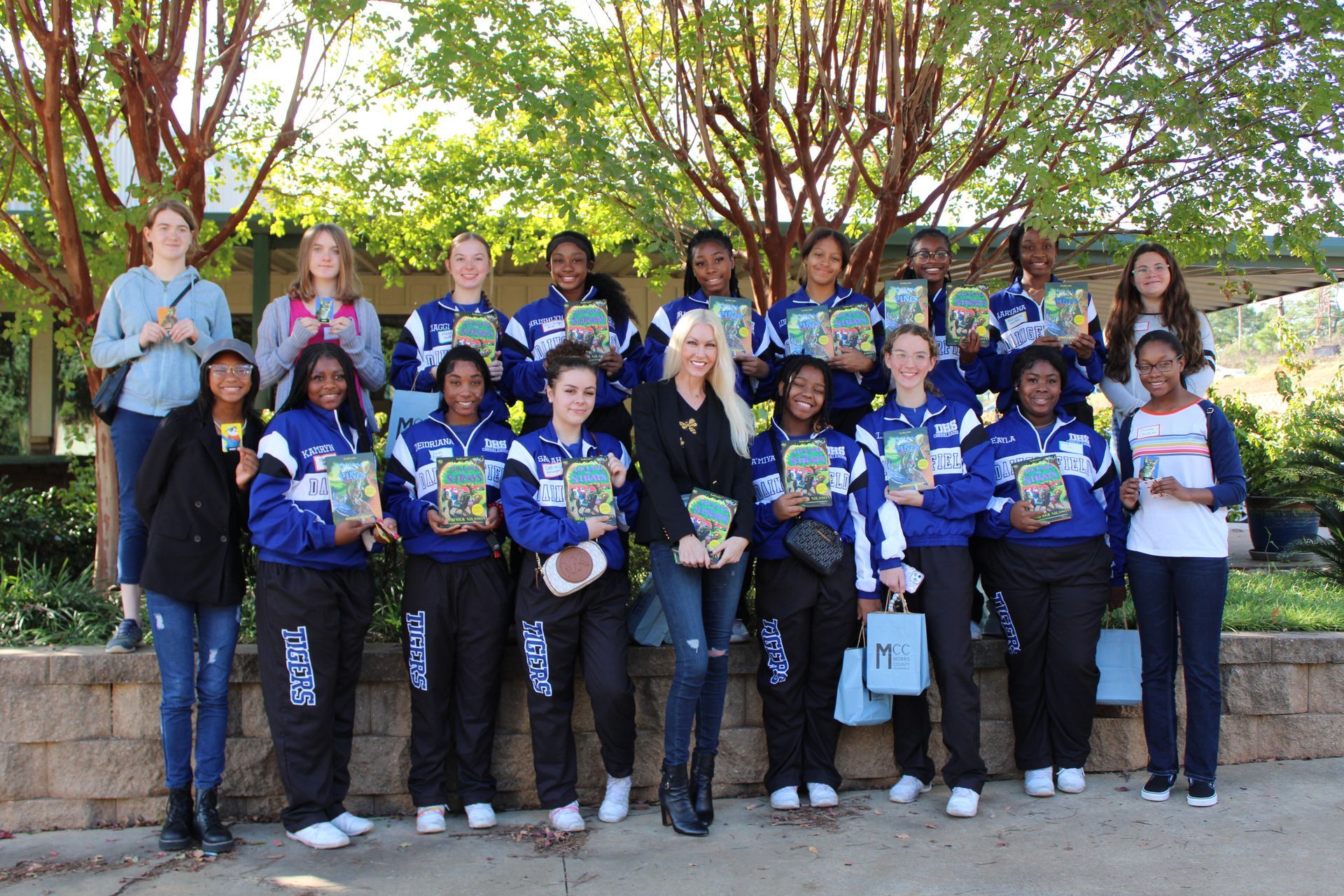 A group of people standing next to each other holding books.