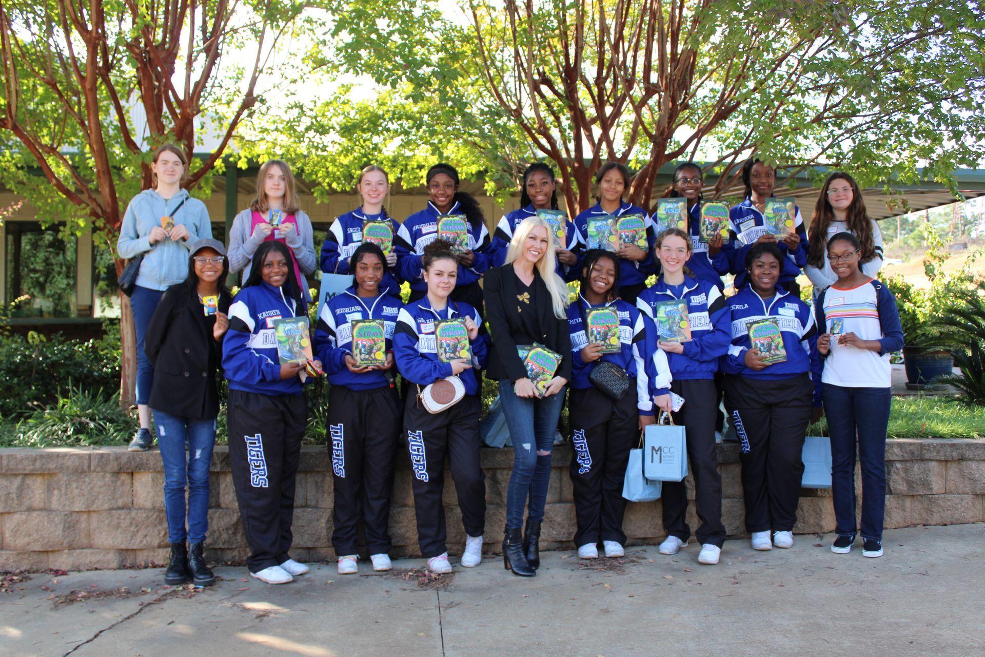 A group of people standing next to each other holding books.