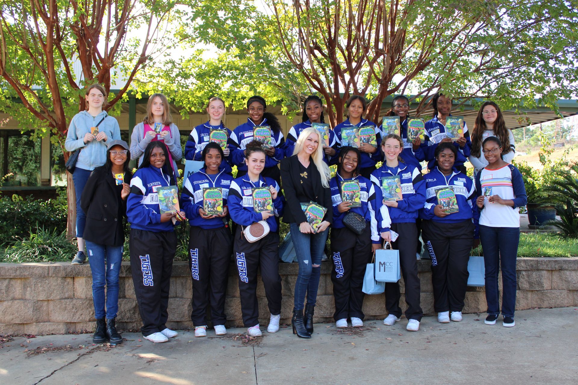 A group of people standing next to each other holding books.