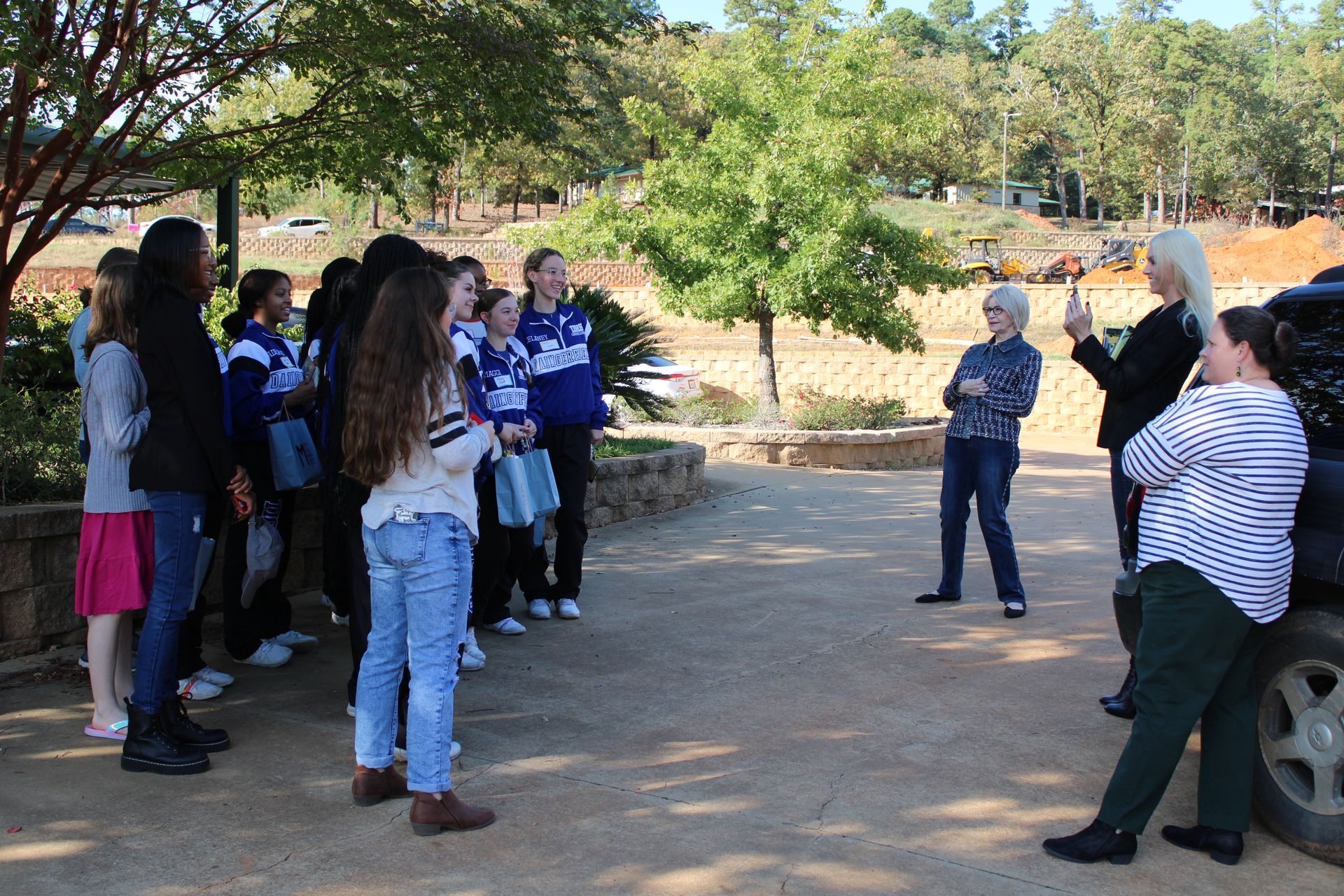 A group of people are standing in a parking lot talking to each other.