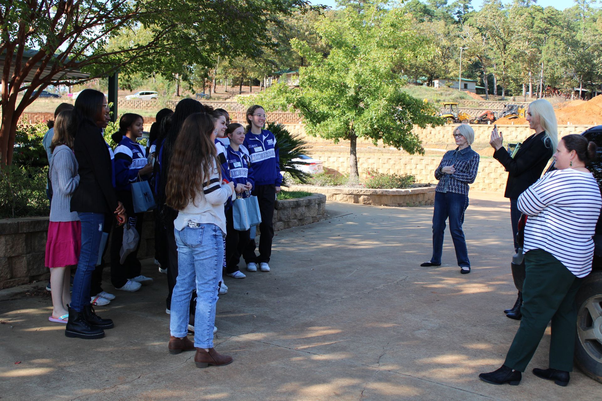 A group of people are standing in a parking lot talking to each other.