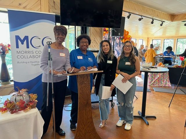 A group of women are standing around a podium in a room.