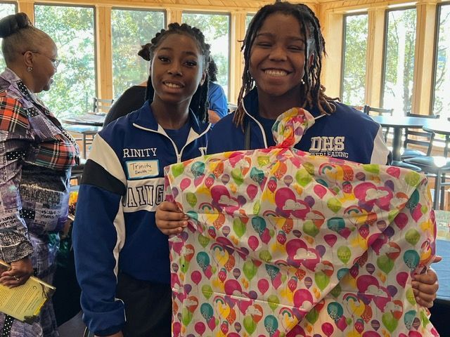 Two girls are holding a piece of wrapping paper with balloons on it.