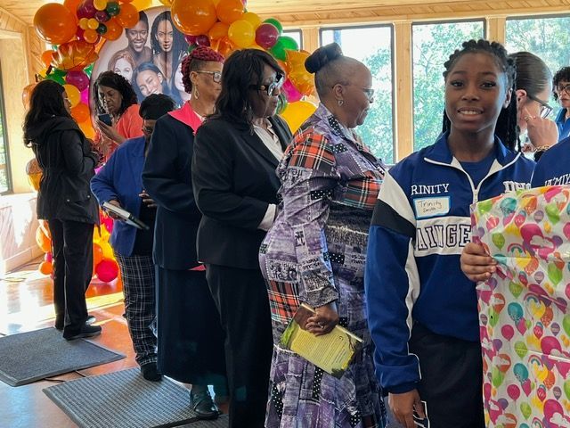 A group of people are standing in a room with balloons in the background.