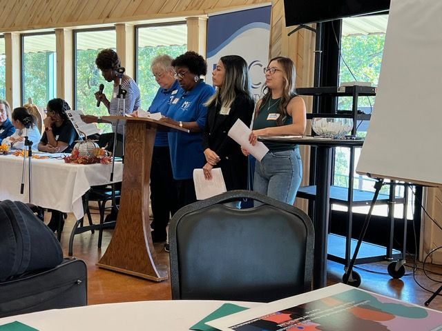 A group of people standing around a podium giving a presentation