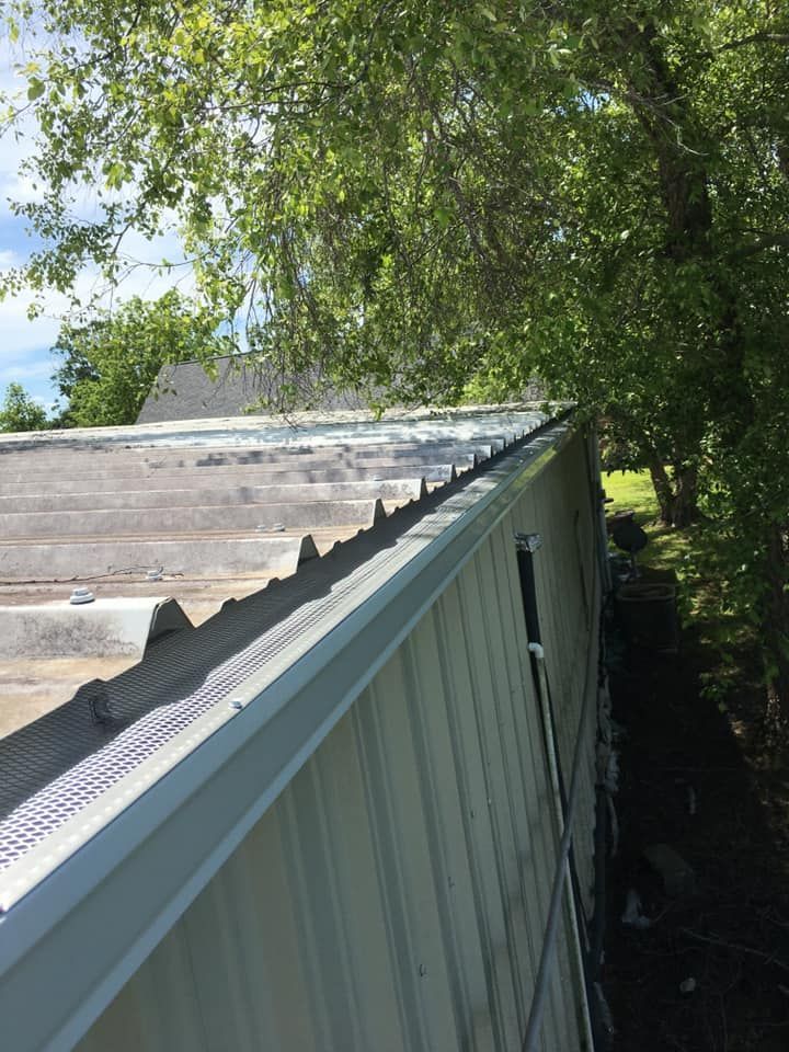 A roof of a building with a gutter on it and trees in the background.