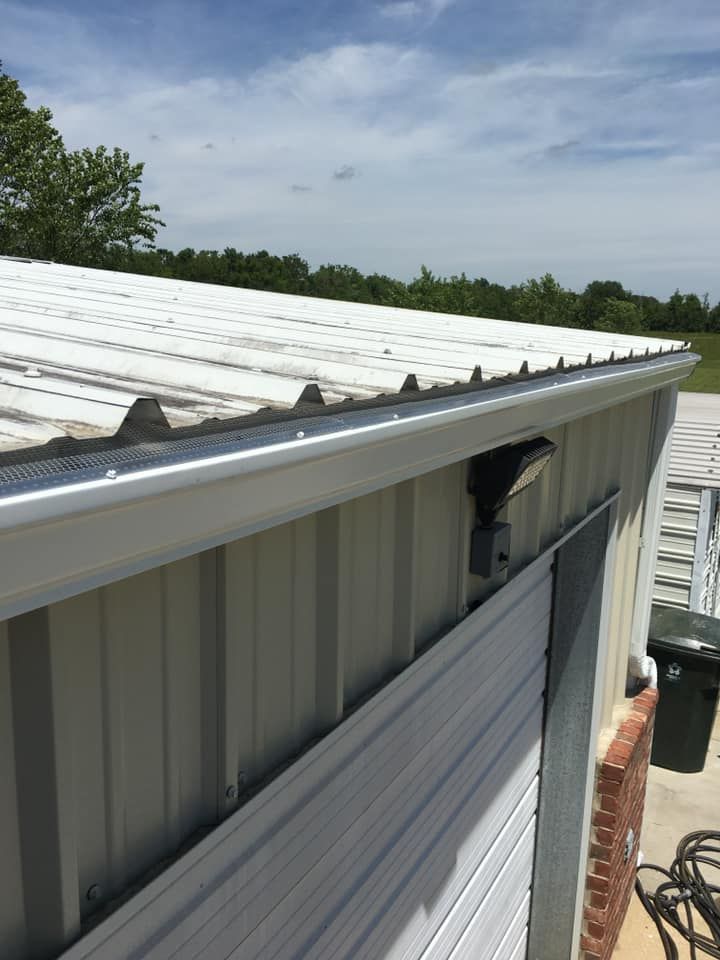 A white metal building with a gutter on the side of it.