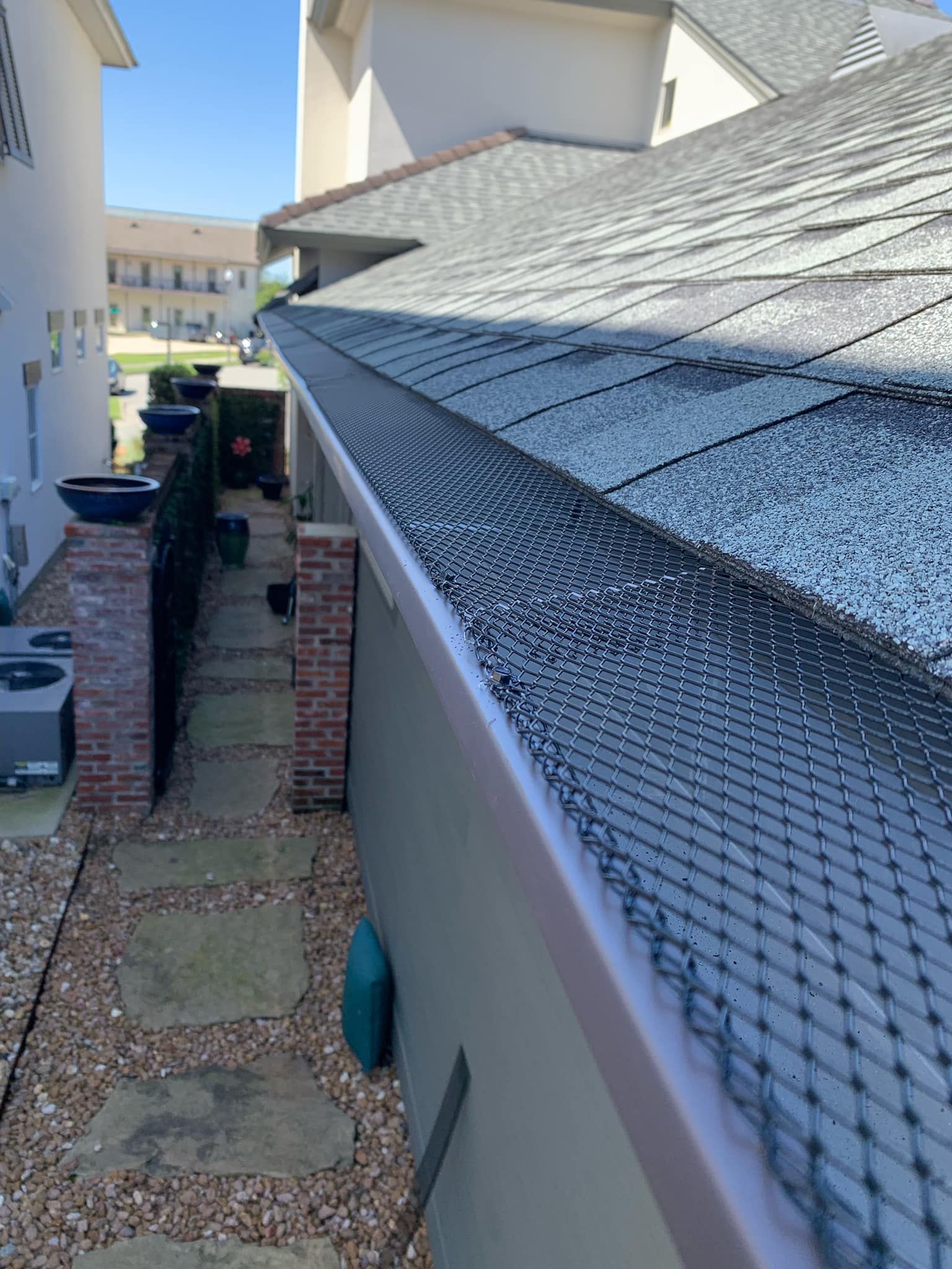 A gutter with a bird net on it is on the side of a house.