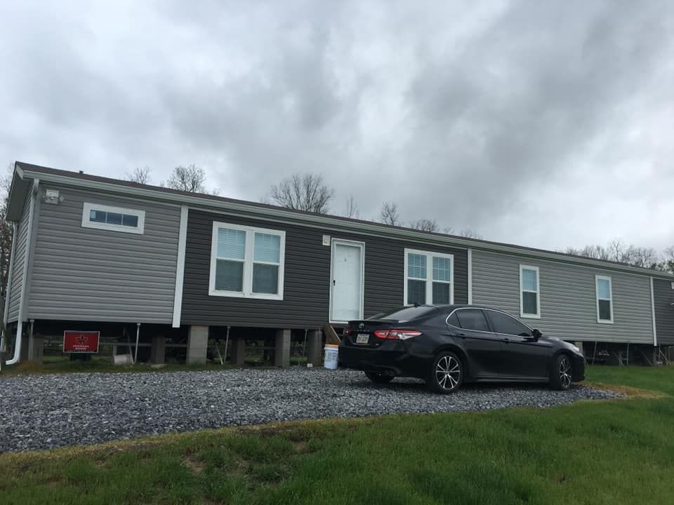 A black car is parked in front of a mobile home.