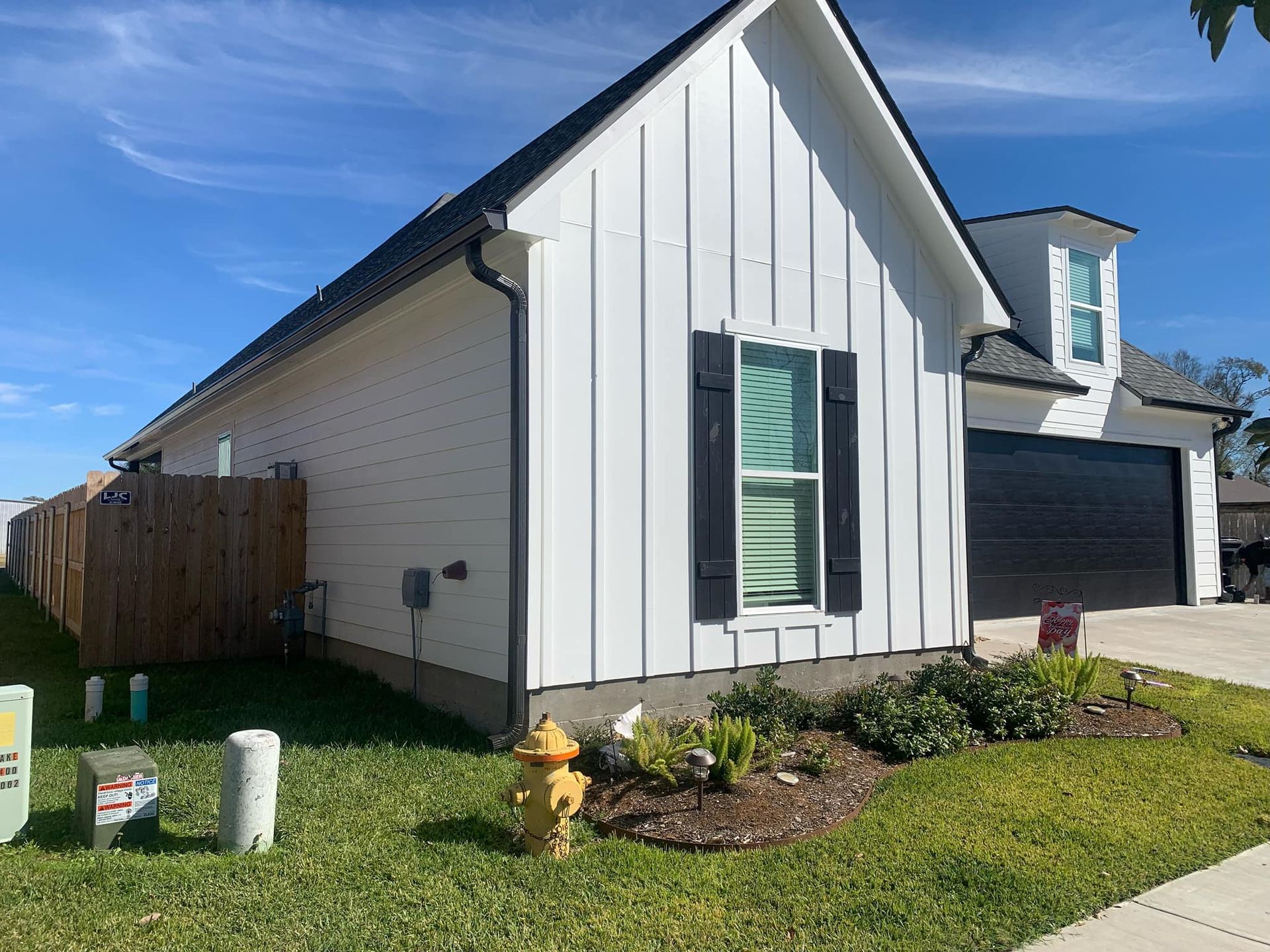 A white house with black shutters and a fire hydrant in front of it.