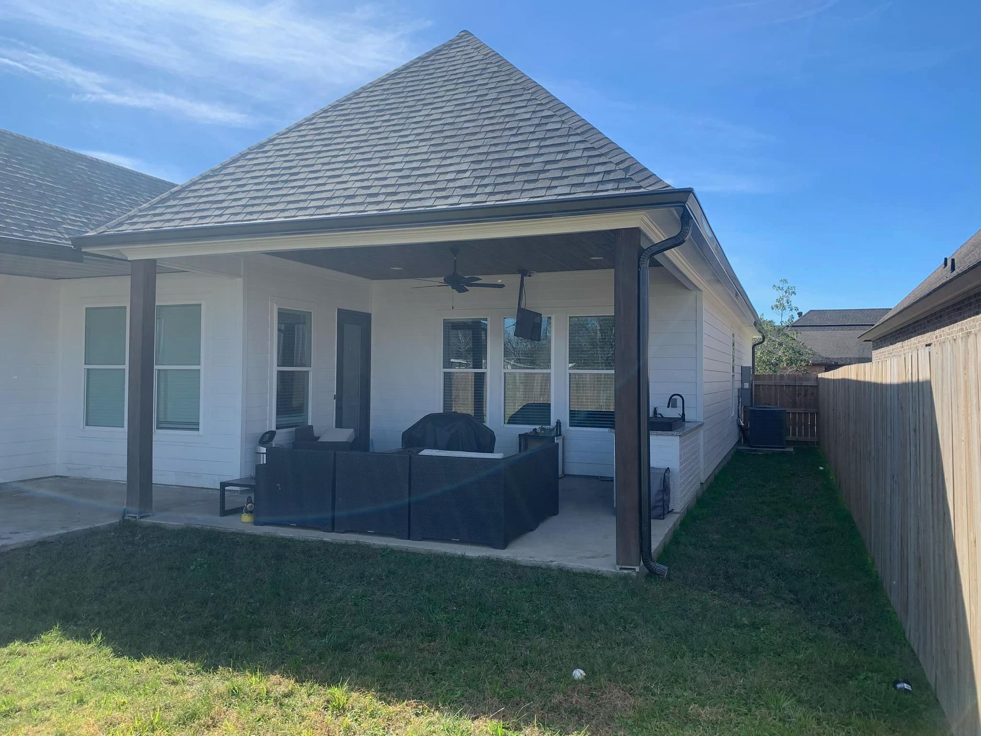 The backyard of a house with a covered patio and a fence.