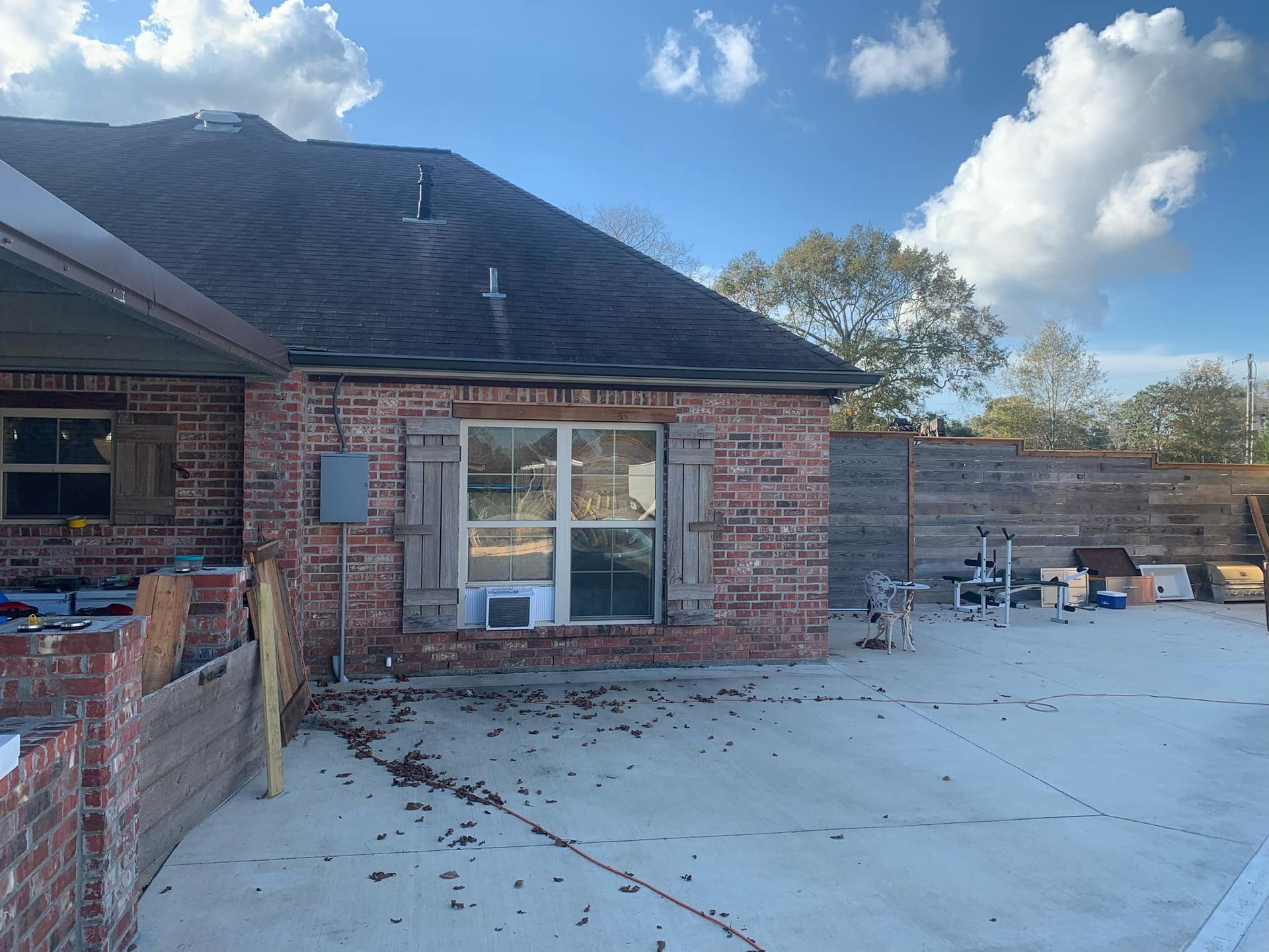 A brick house with a large window and a concrete driveway in front of it.