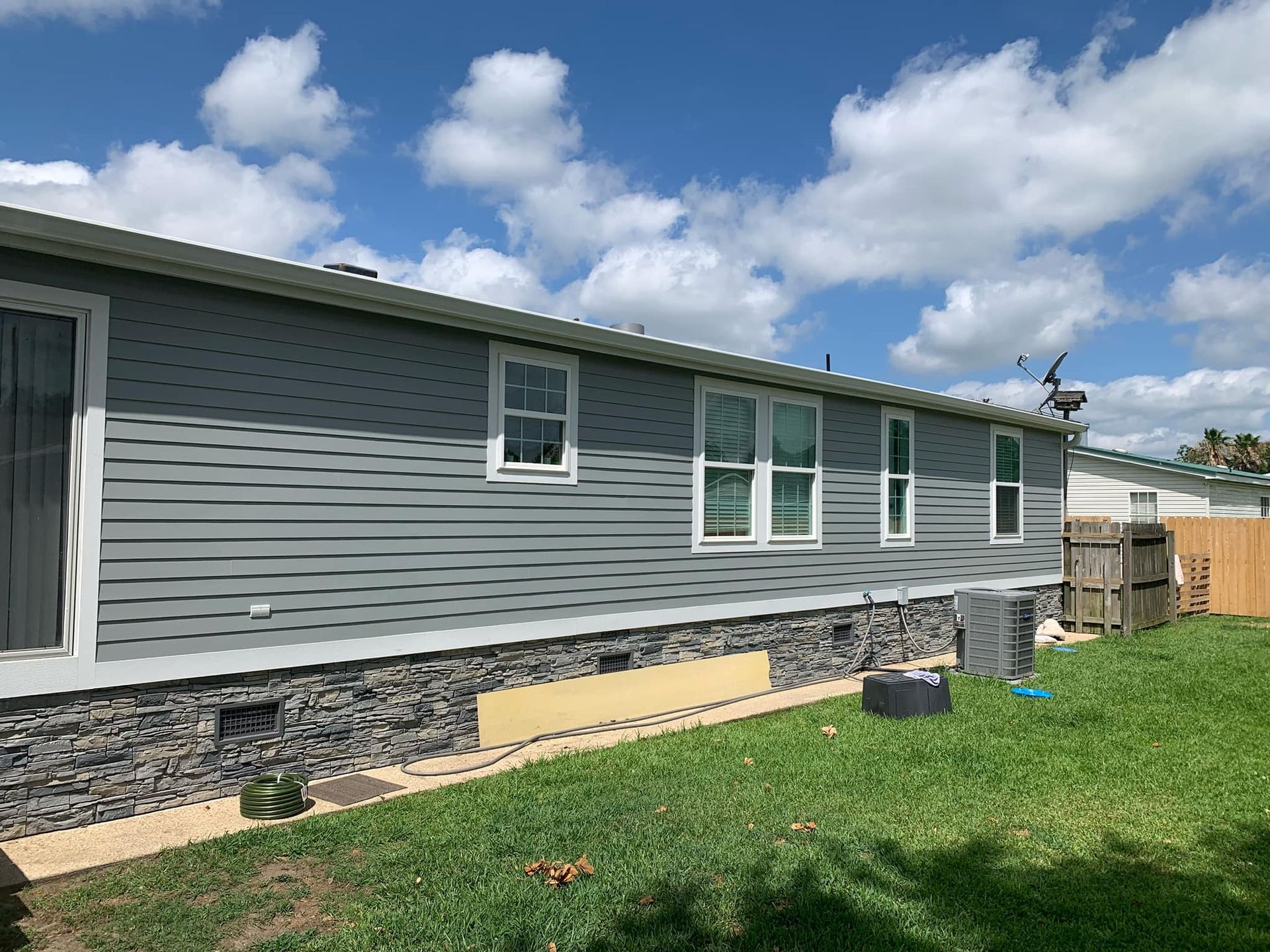 A mobile home with a lot of windows is sitting on top of a lush green lawn.
