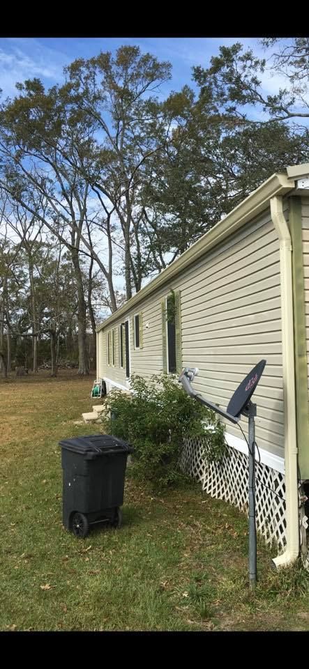 A mobile home with a trash can in front of it.