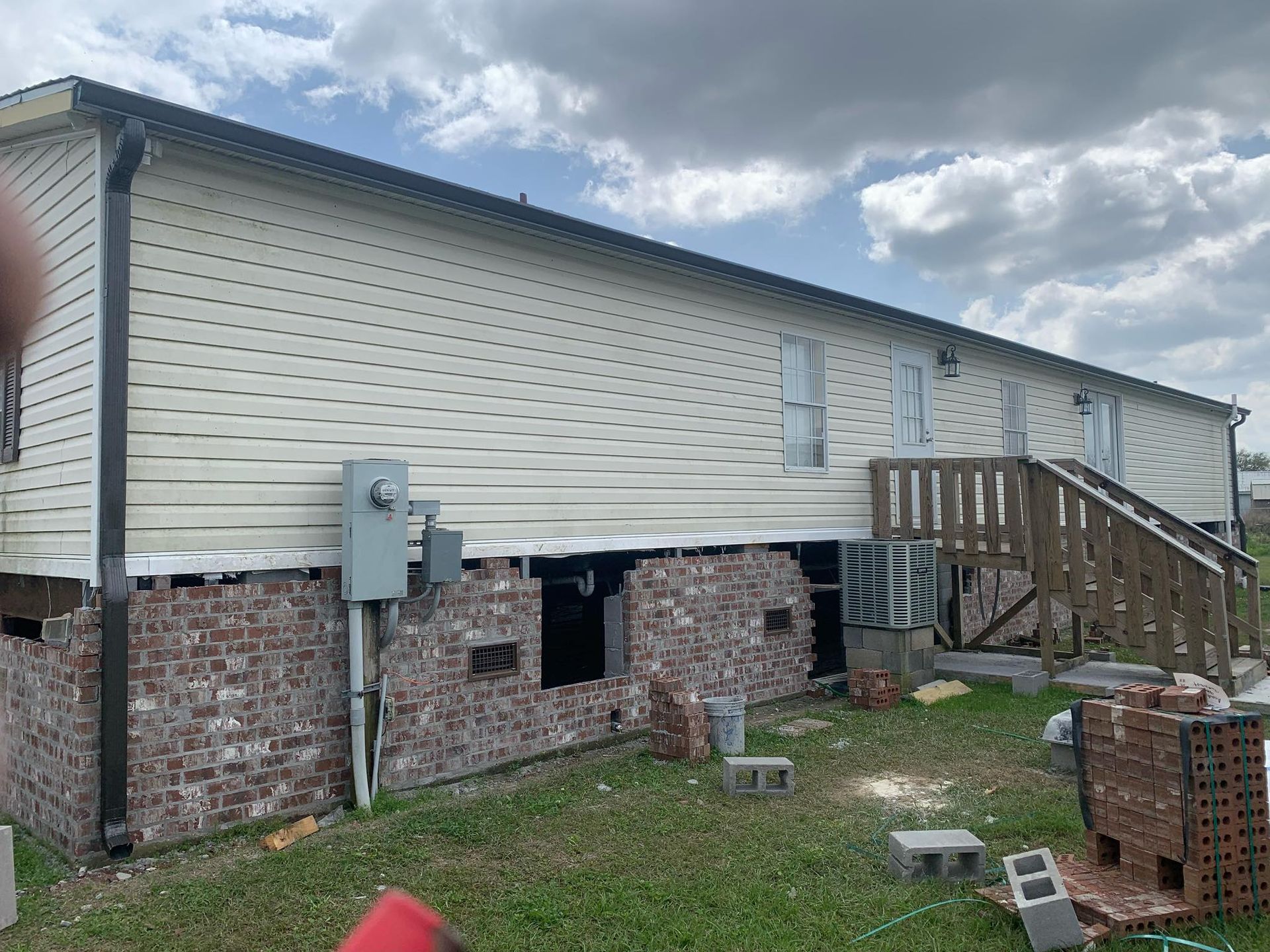 A house with a brick wall and a white siding is being built.