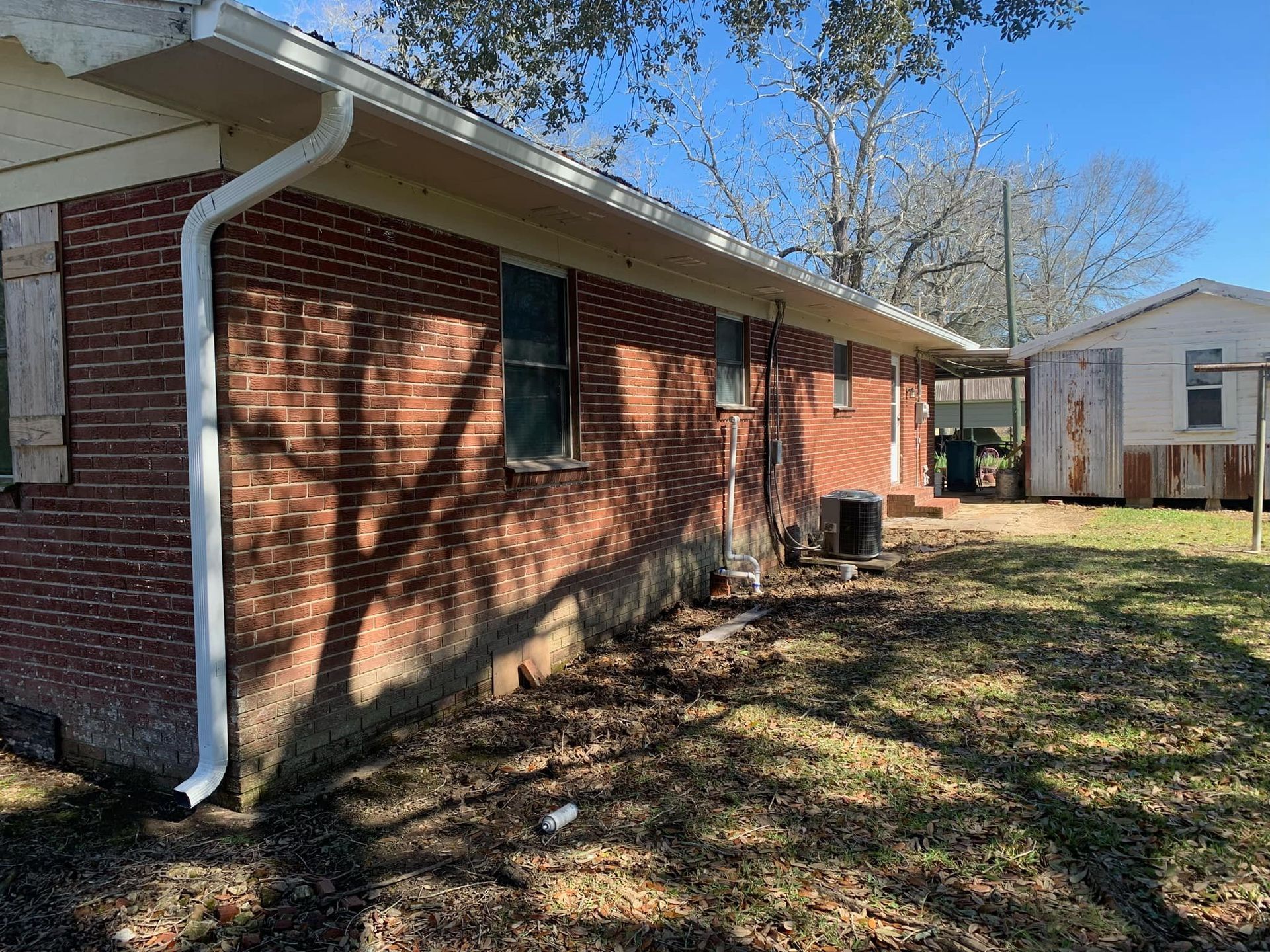 A brick house with a white gutter on the side of it.