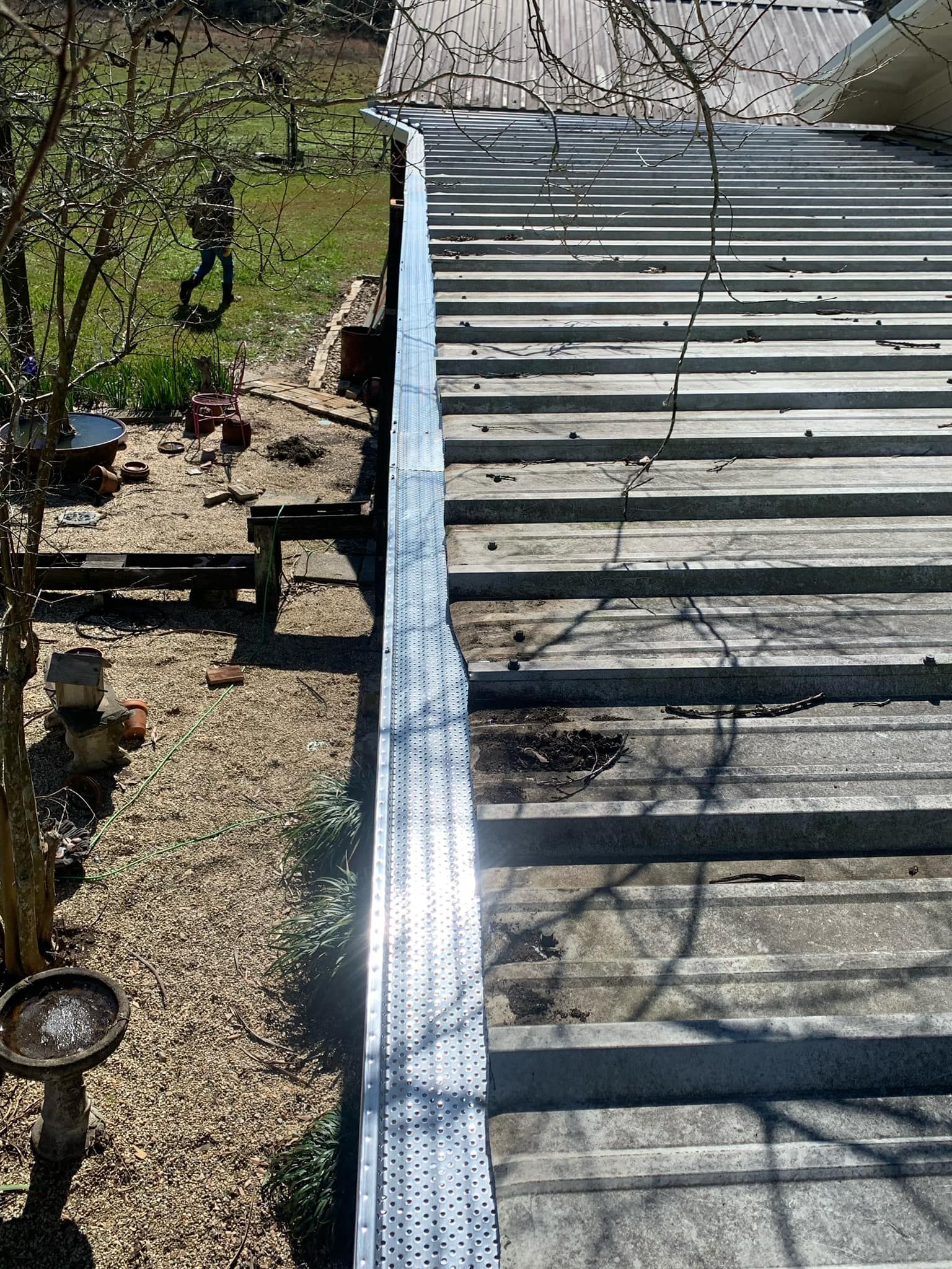 A roof with a metal railing is sitting on top of a gravel yard.