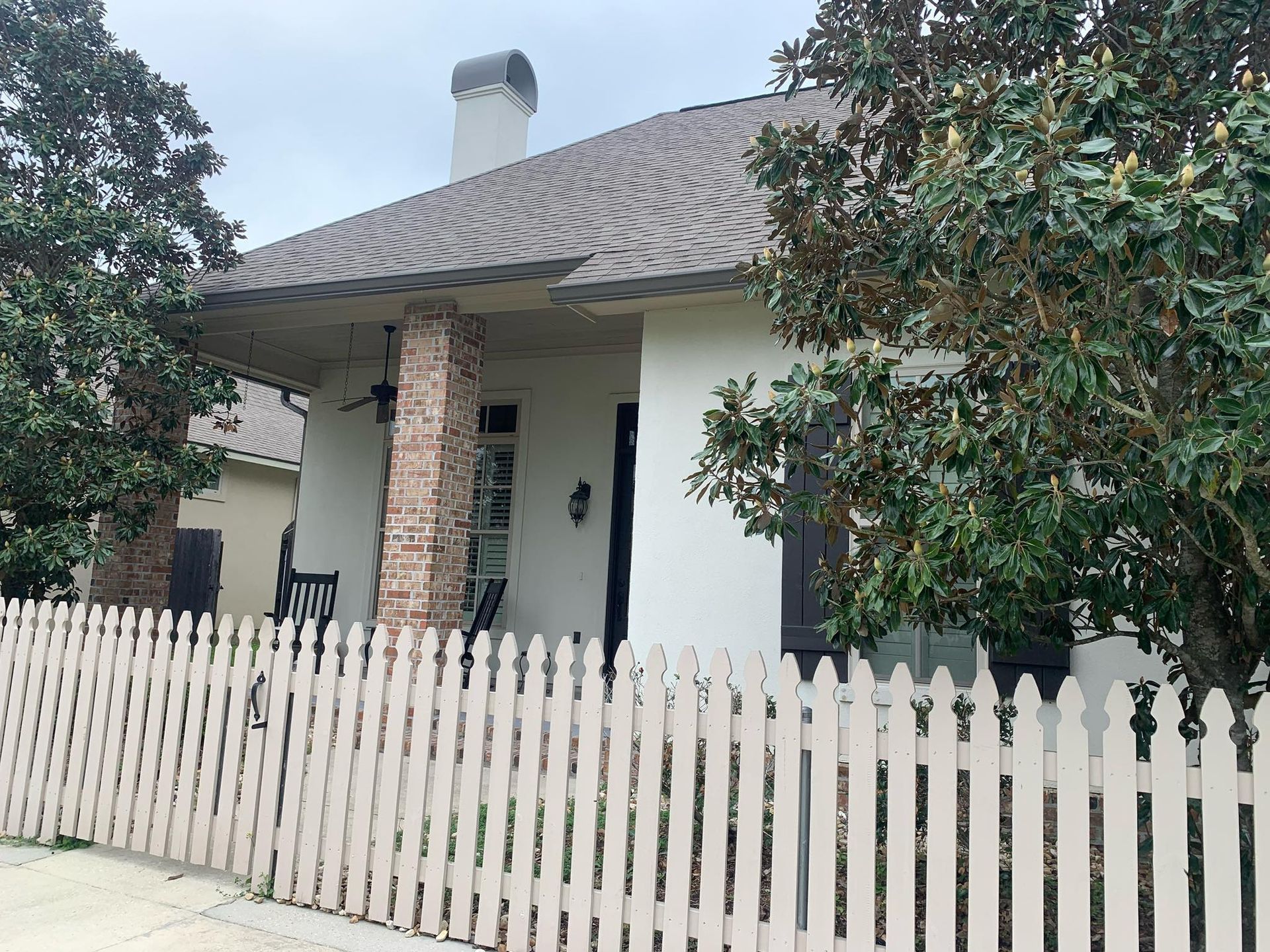 A white picket fence is in front of a house.
