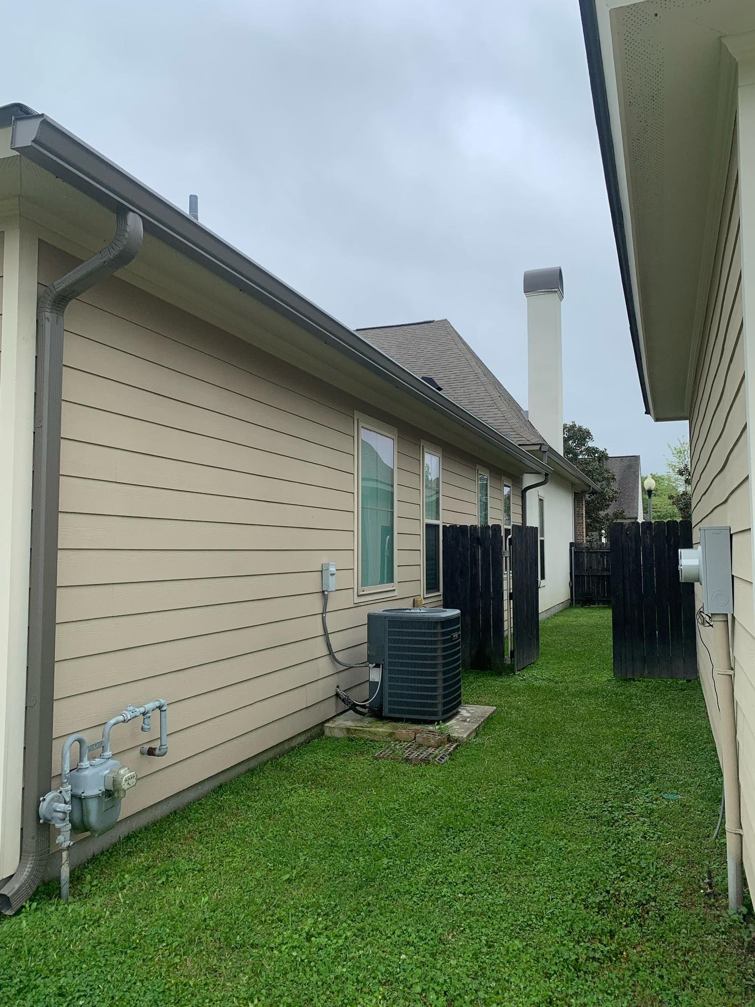 A house with a gutter on the side of it and a lawn in front of it.
