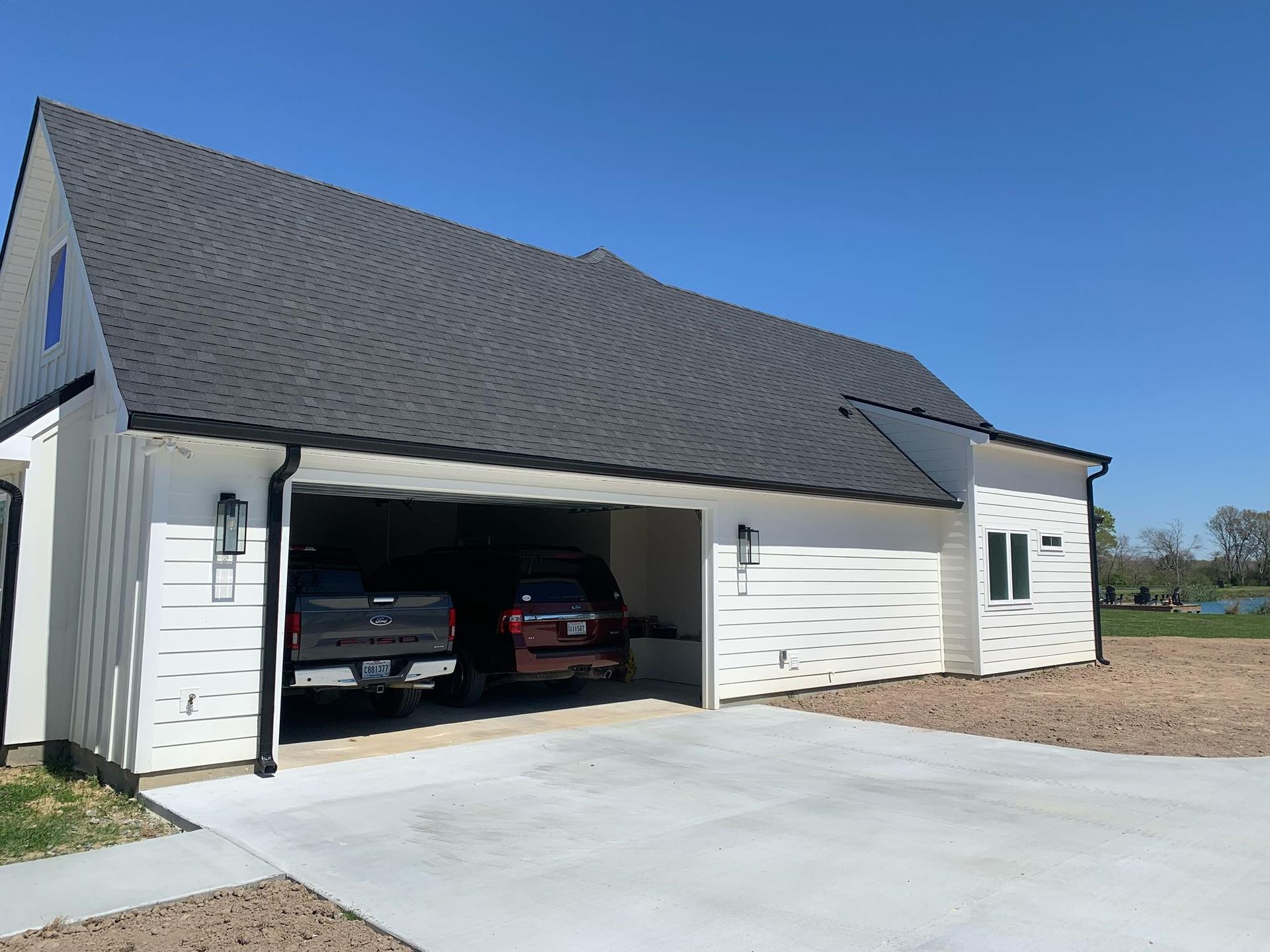 Two cars are parked in a garage next to a house.