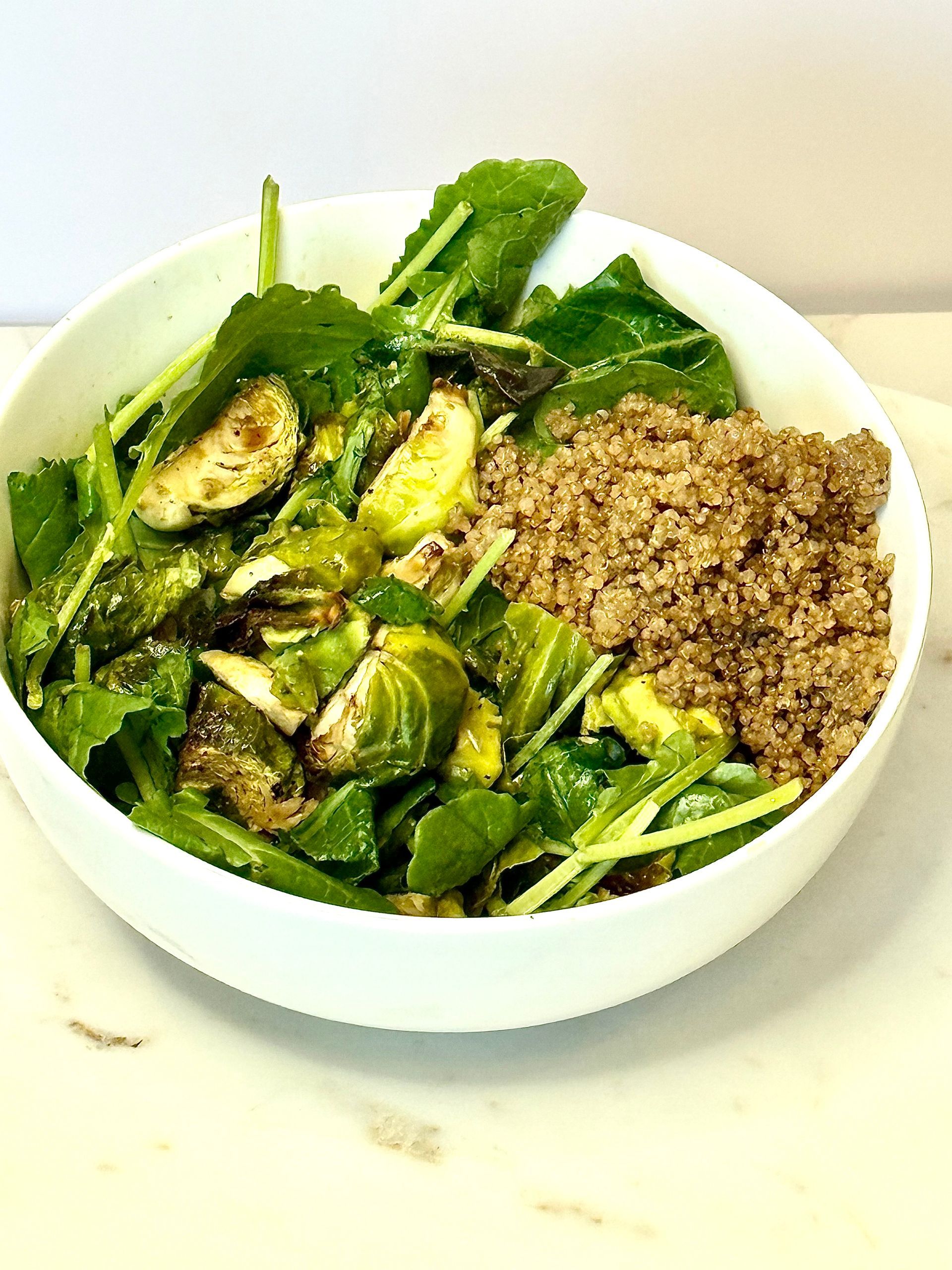Bowl of arugula, roasted Brussels sprouts, and quinoa.