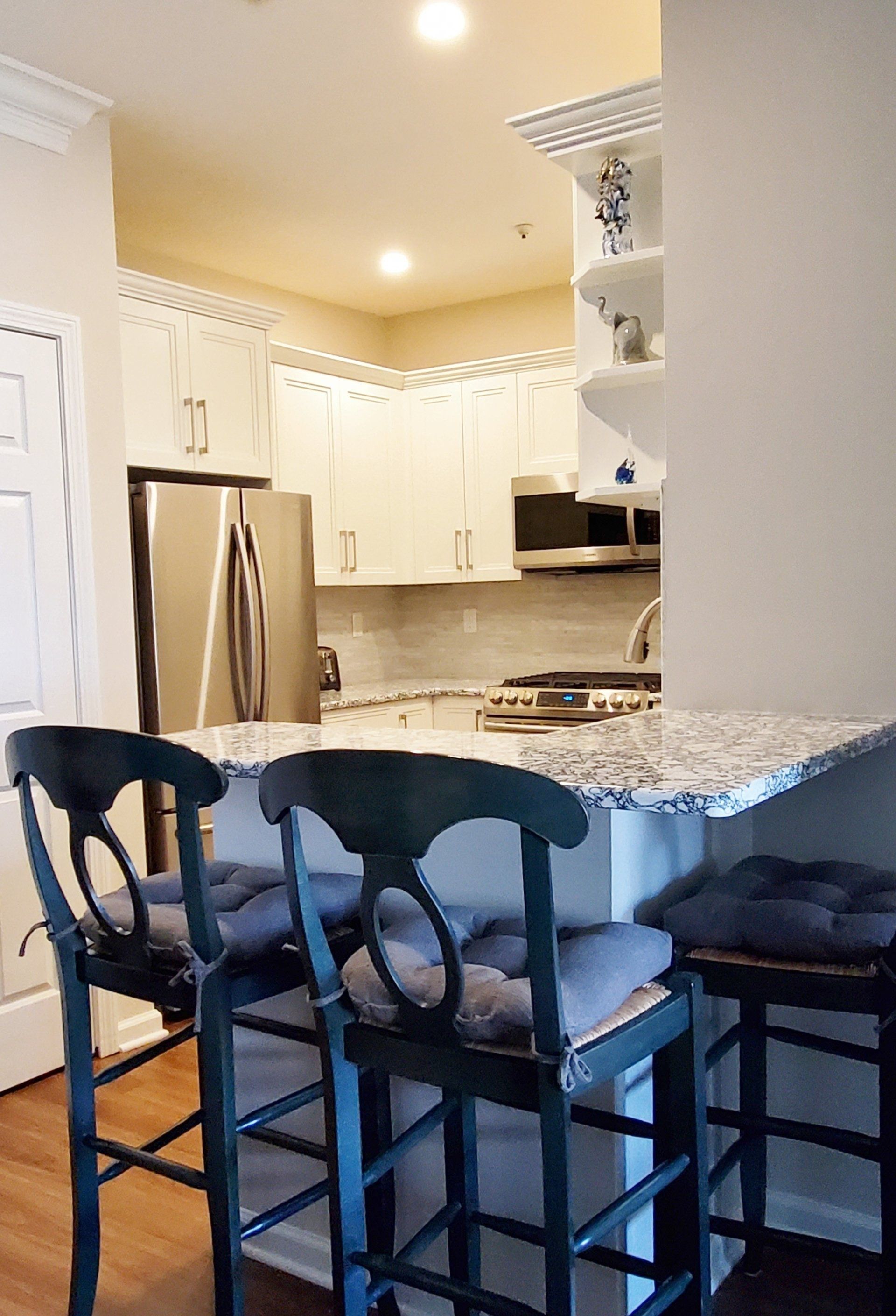 A kitchen with two bar stools and a granite counter top.