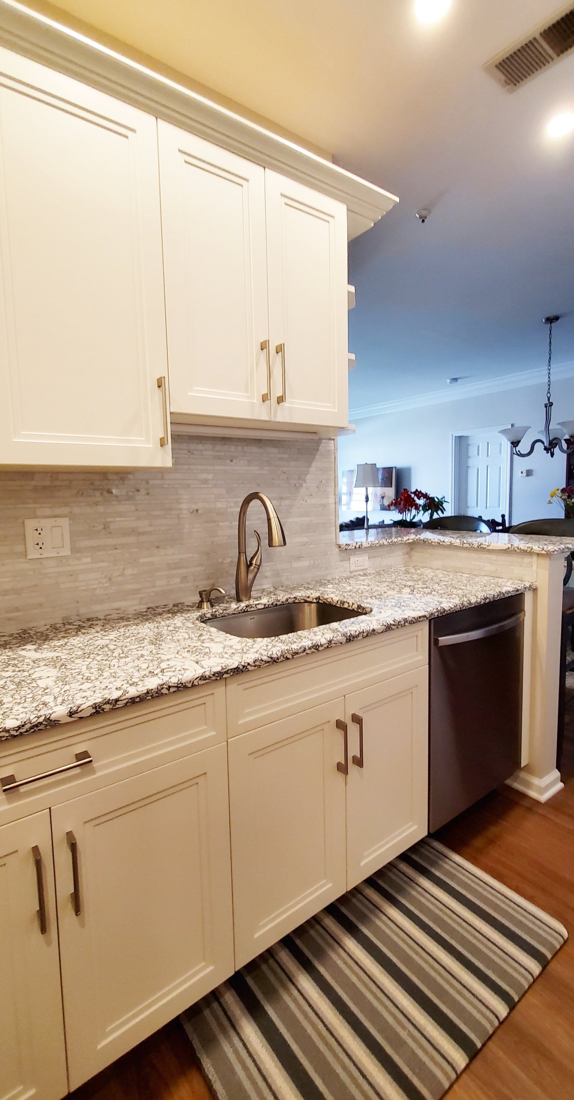 A kitchen with white cabinets , granite counter tops , a sink and a dishwasher.