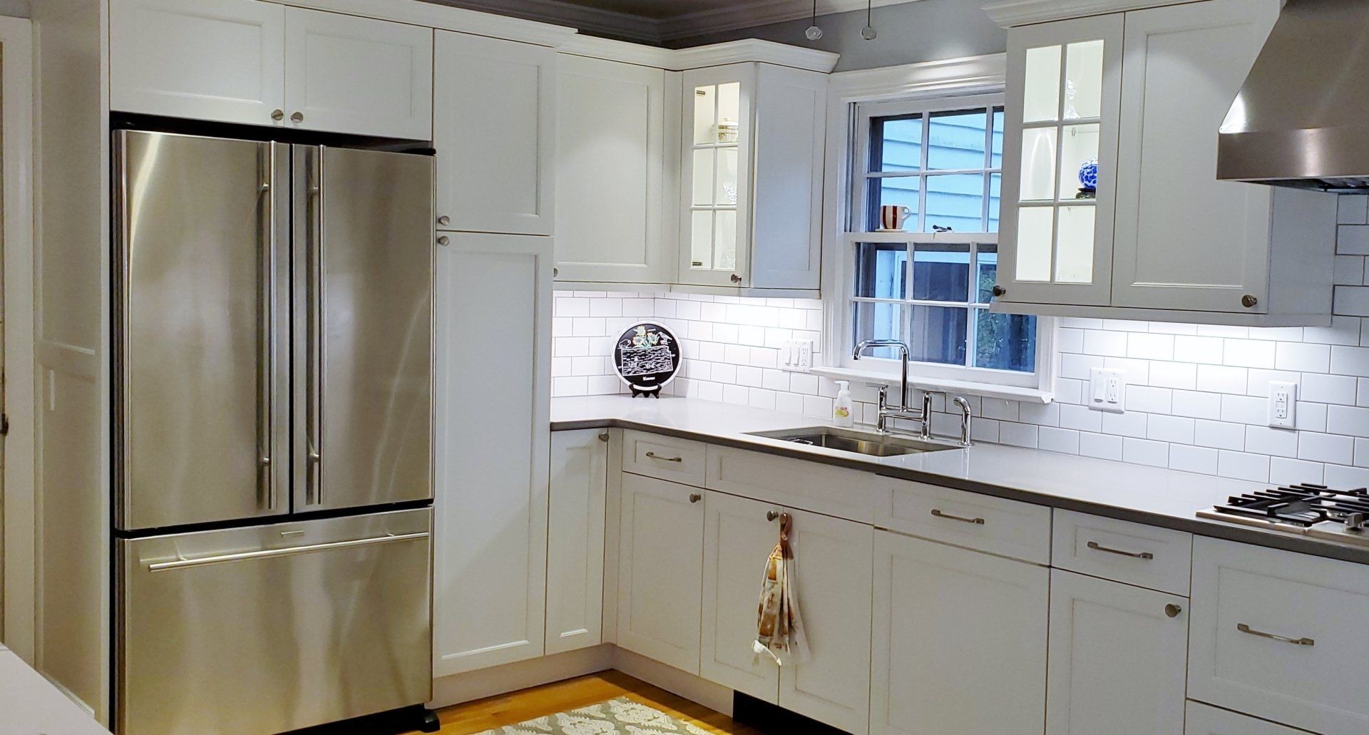 A kitchen with white cabinets and a stainless steel refrigerator