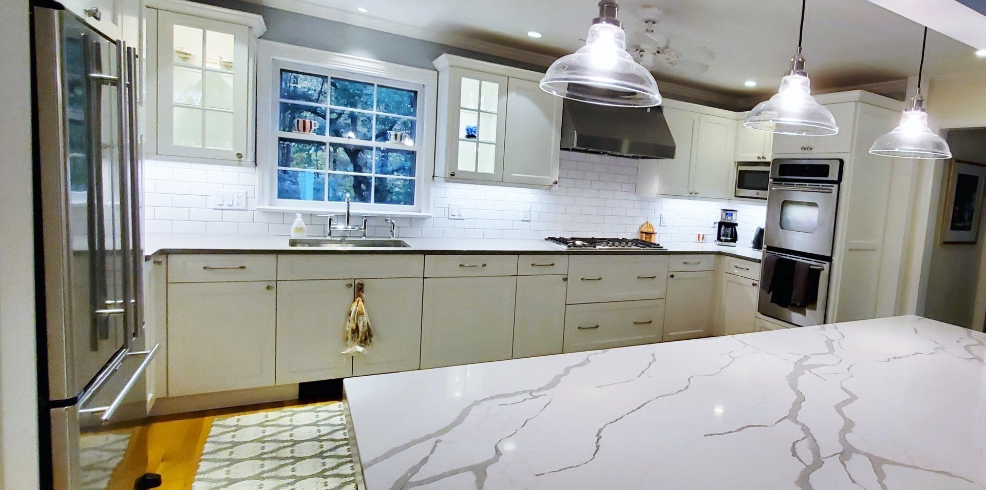 A kitchen with white cabinets , stainless steel appliances , and a large island.