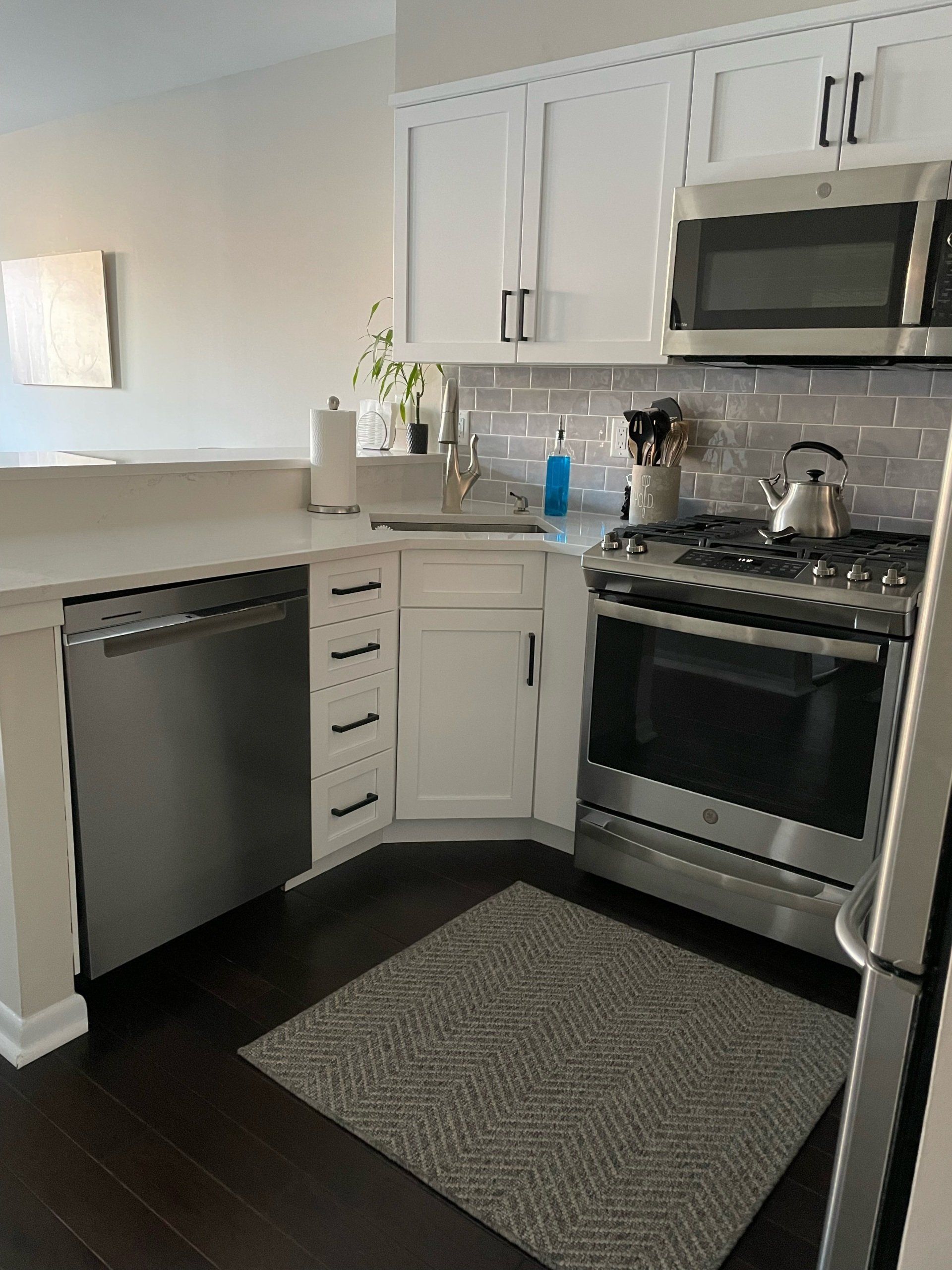 A kitchen with stainless steel appliances and white cabinets.