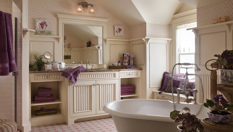 A bathroom with a tub , sink , mirror and purple towels