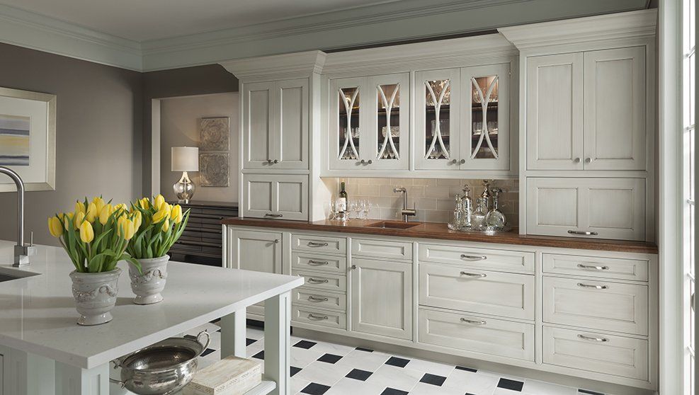 A kitchen with white cabinets and a black and white tile floor.