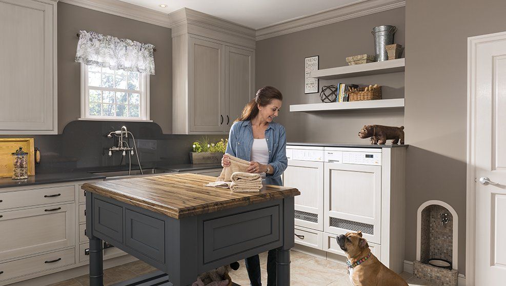 A woman is standing next to a dog in a kitchen.
