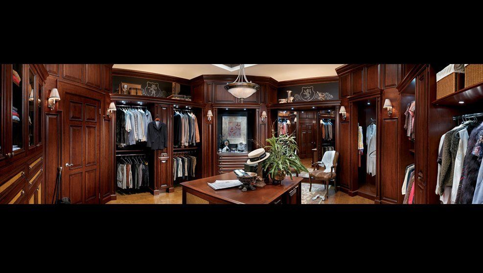 A large walk in closet filled with lots of clothes and a table.