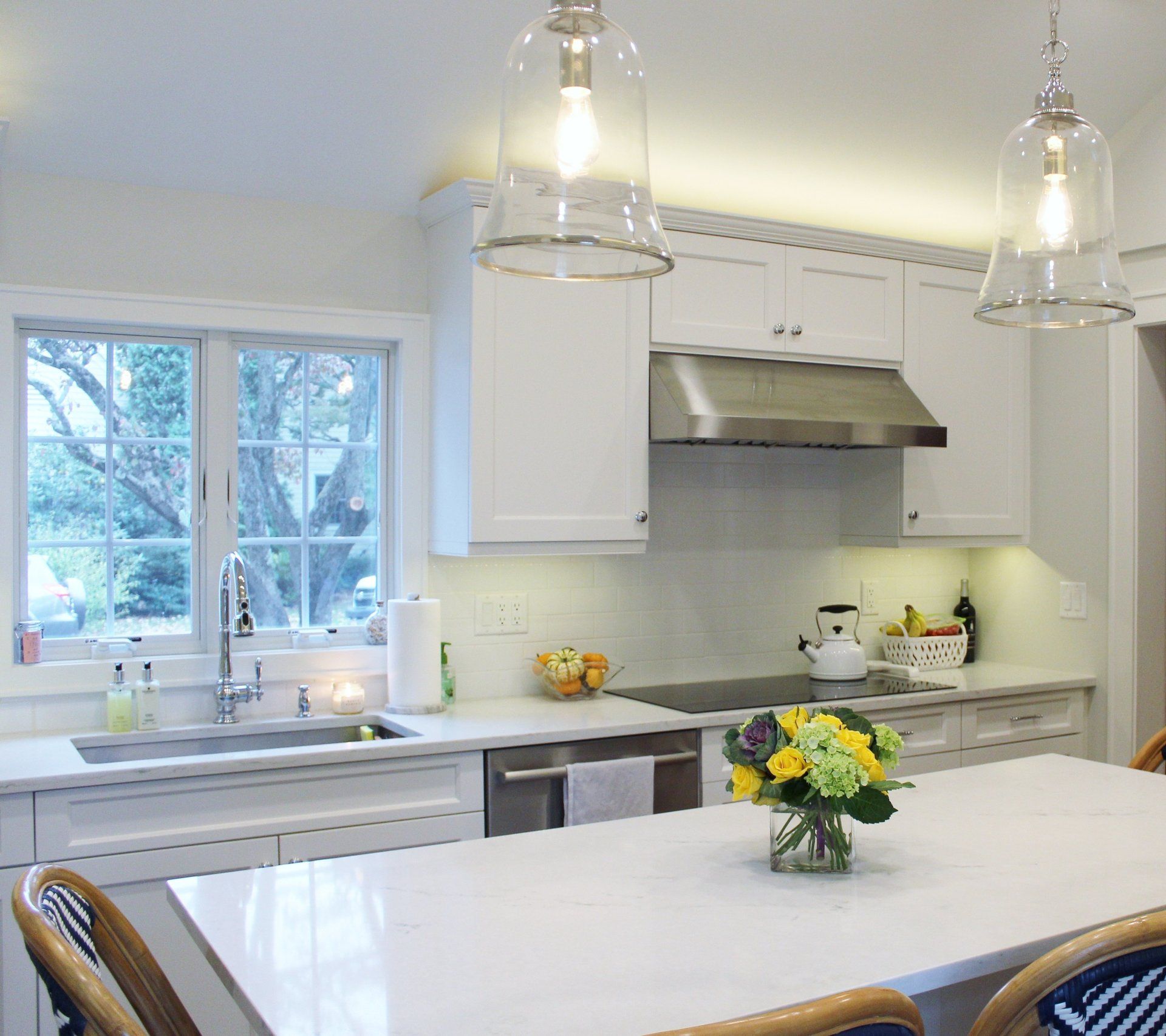 A kitchen with a table and chairs and a vase of flowers on it