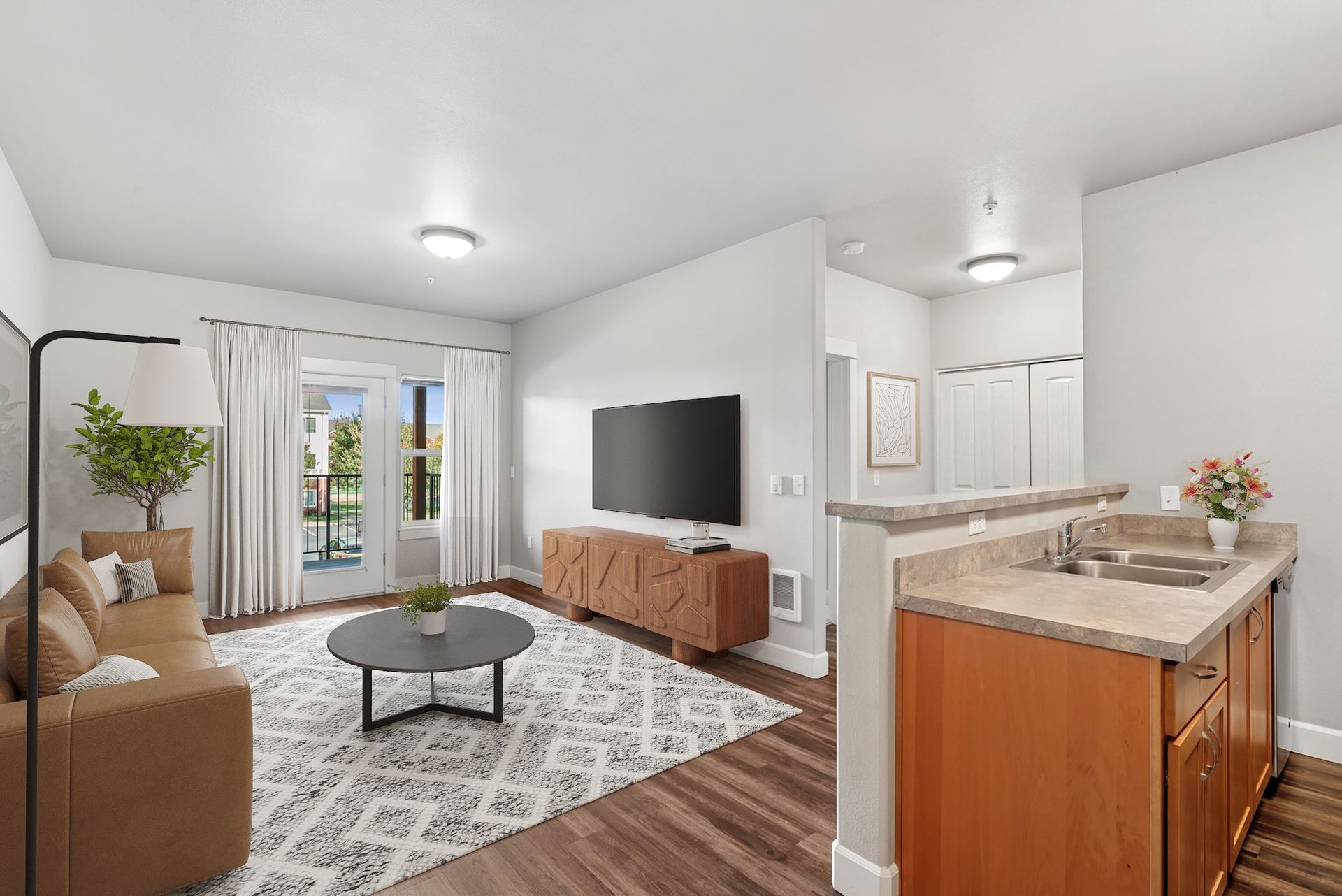 Modern living room with TV, beige couch, coffee table, and balcony access.