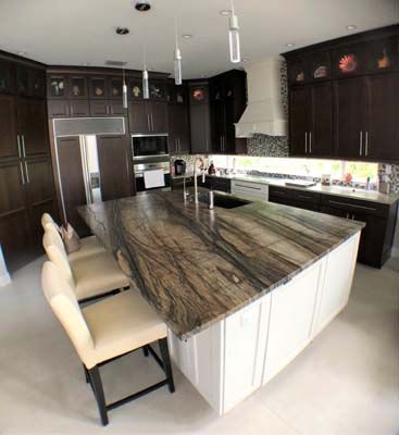 A kitchen with a large granite counter top and white cabinets.
