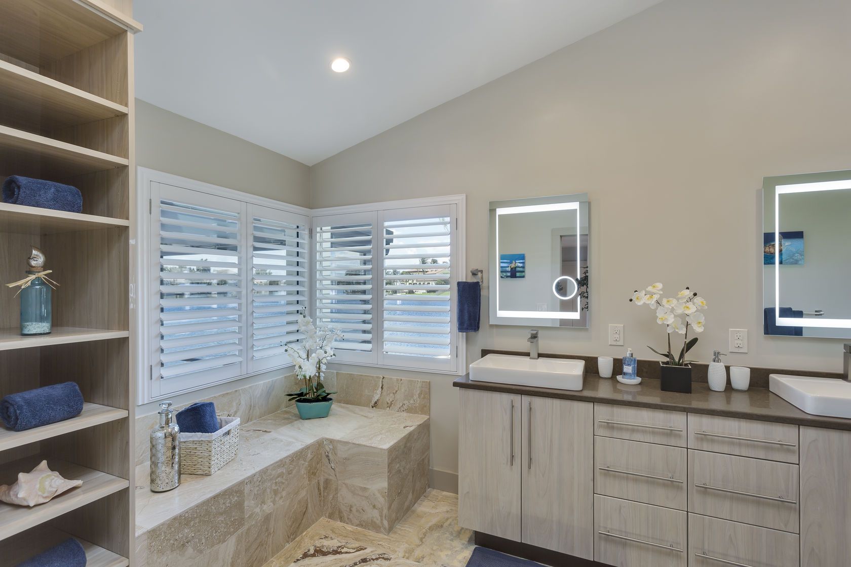 A bathroom with two sinks , two mirrors and a tub.