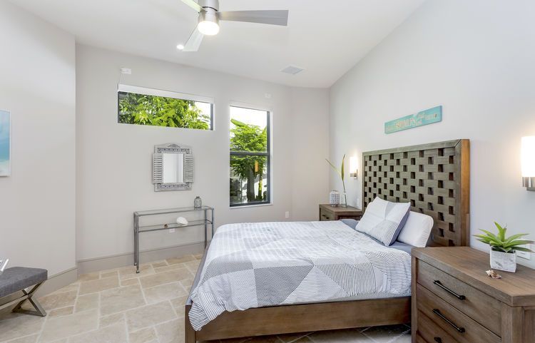 A bedroom with a bed , nightstand , dresser and ceiling fan.