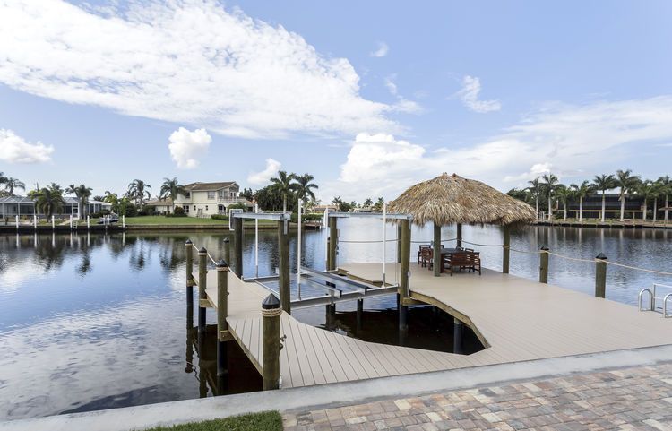 A dock with a thatched hut on top of it in the middle of a lake.