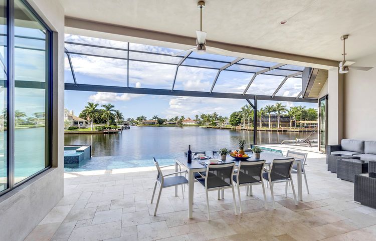 A patio with a table and chairs overlooking a lake.