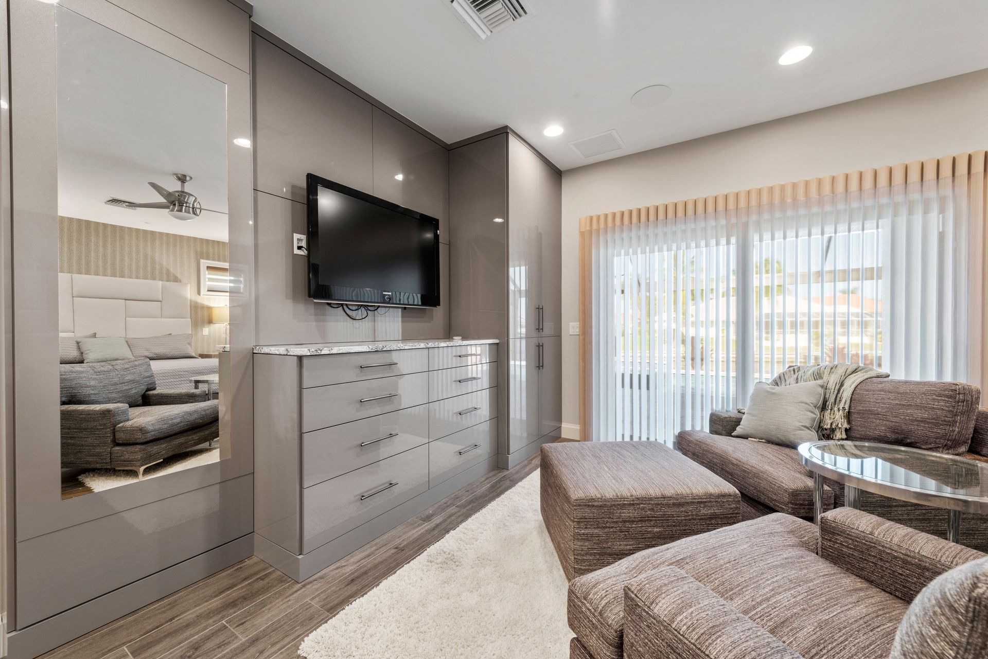 A living room with a couch , chairs , ottoman and a flat screen tv.