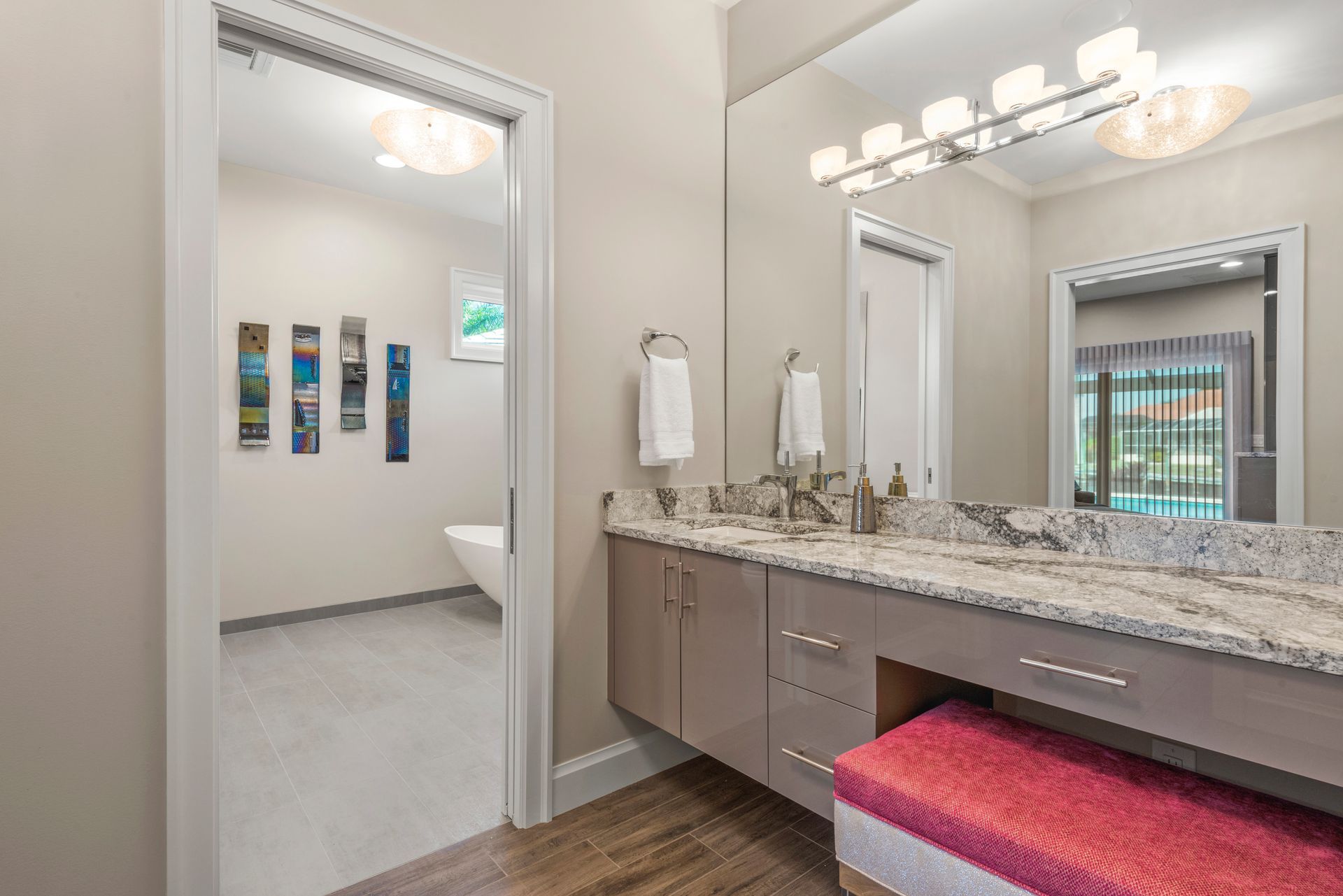 A bathroom with two sinks , a large mirror and a pink bench.