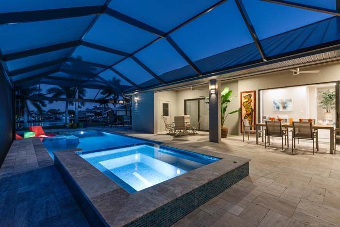 There is a swimming pool and a hot tub in the backyard of a house.