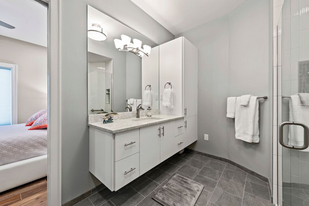 A bathroom with two sinks , a mirror and a walk in shower.